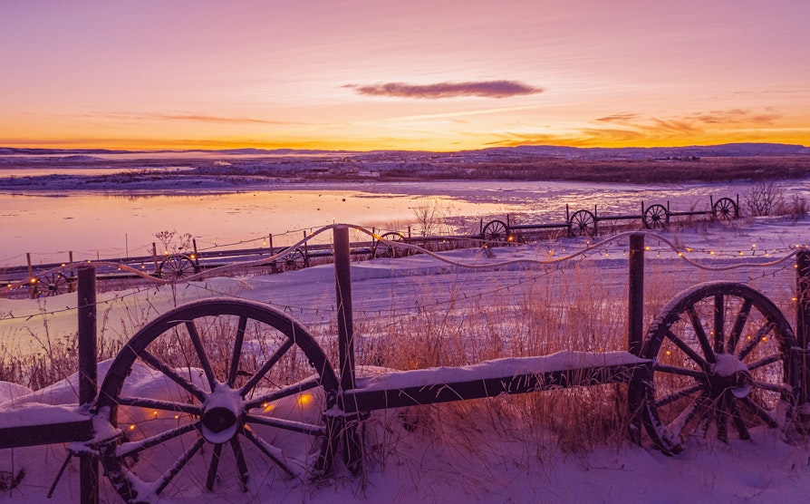 Snø på gjerde og jorde med et lite vann og fin himmel i bakgrunnen i Varangerbotn, Finnmark. Lilla farger. Extra.