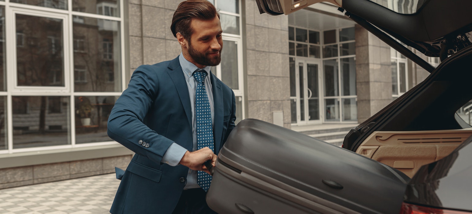 Een zakenman in klassieke kleding gaat op reis met een auto