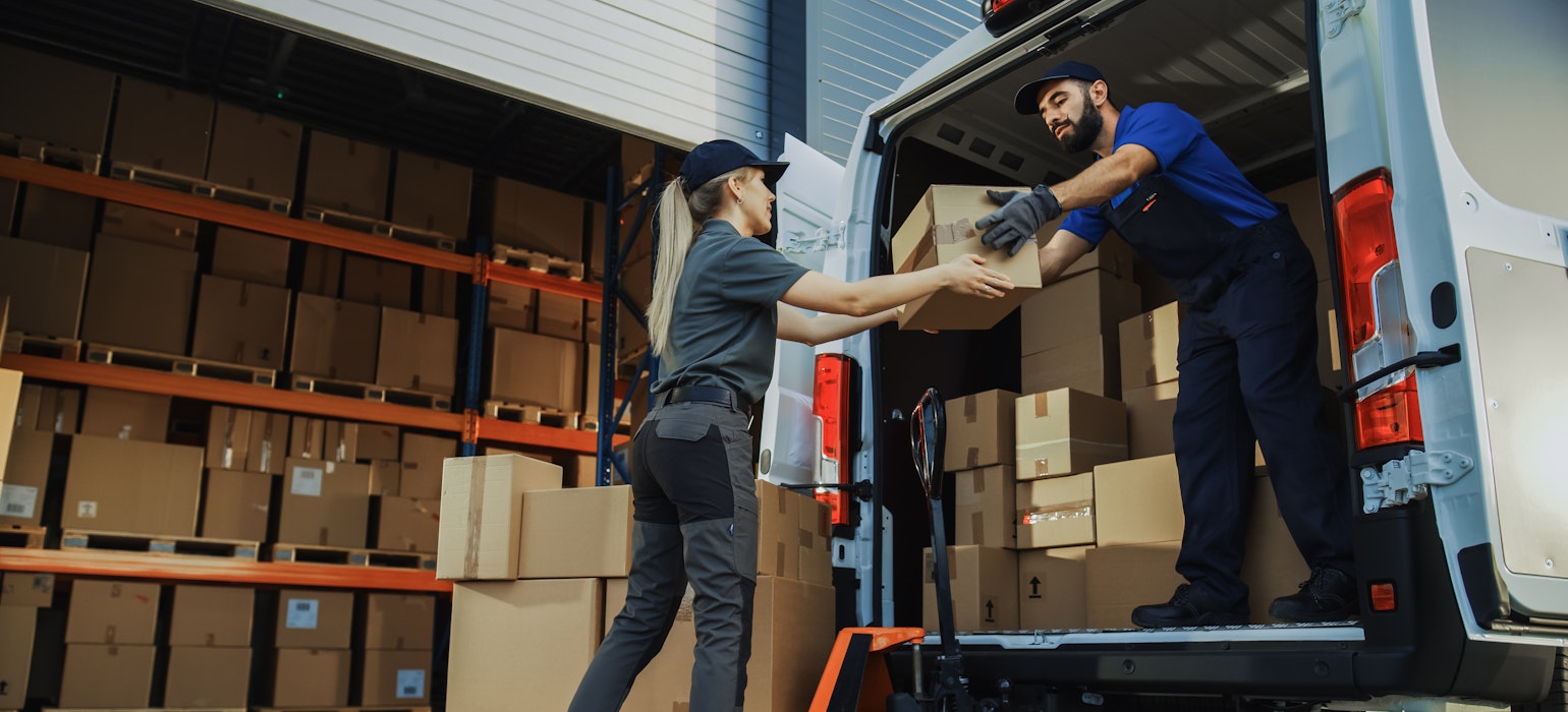 Une équipe diversifiée de travailleurs charge manuellement le camion de livraison avec des boîtes en carton, des commandes en ligne et des achats en ligne.