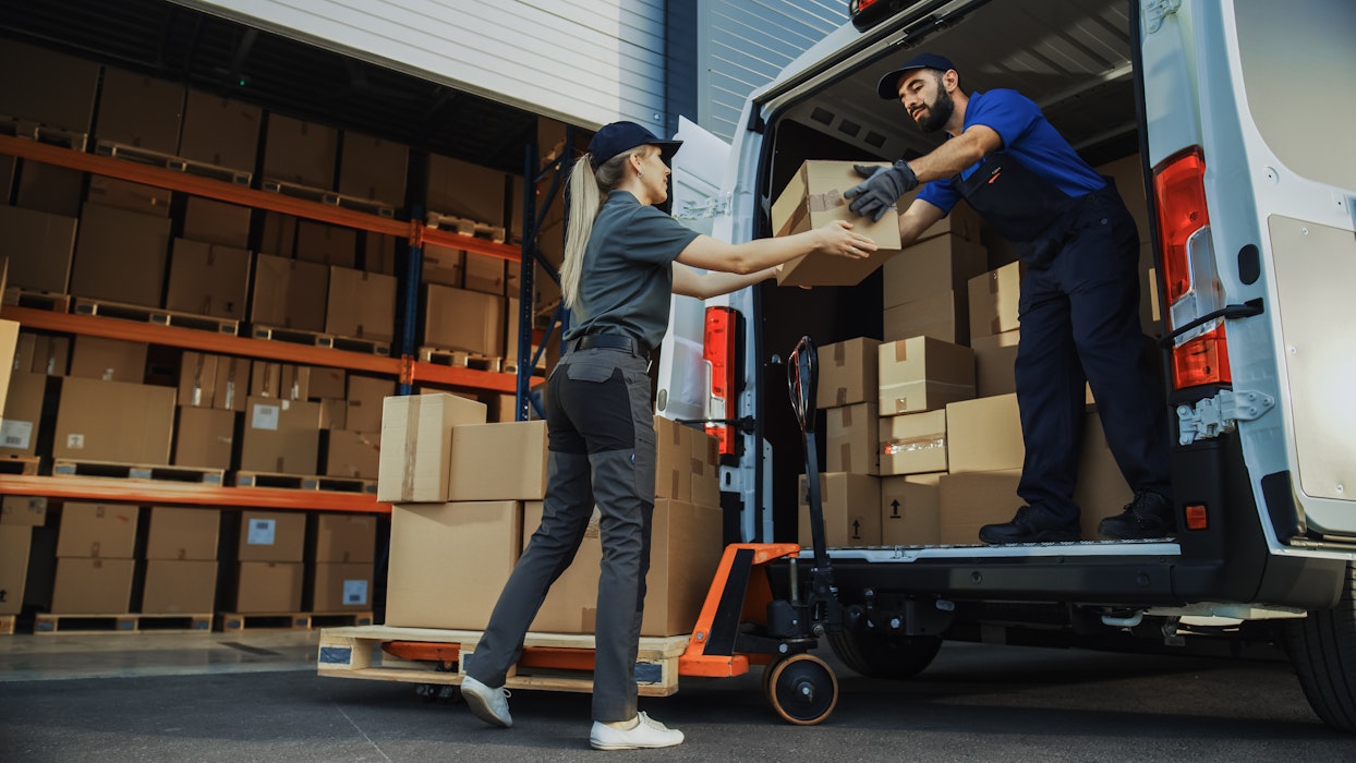Een divers team van werknemers laadt met de hand de bestelwagen met kartonnen dozen, online bestellingen en e-commerce aankopen.