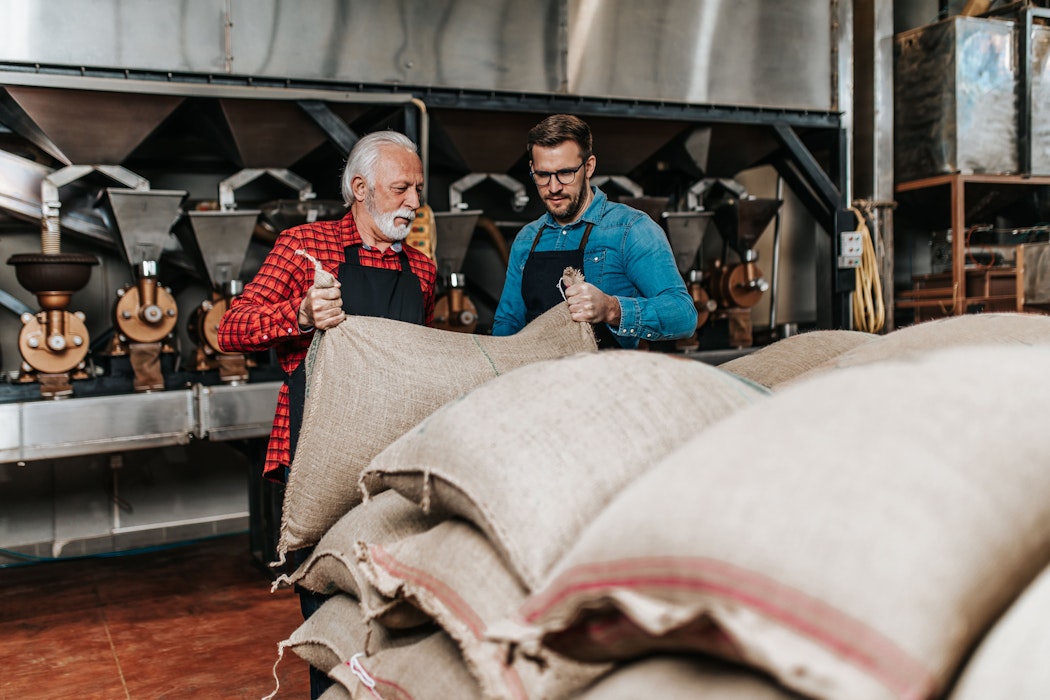 Oudere en jonge man, vader en zoon, werken samen in koffiebranderij.
