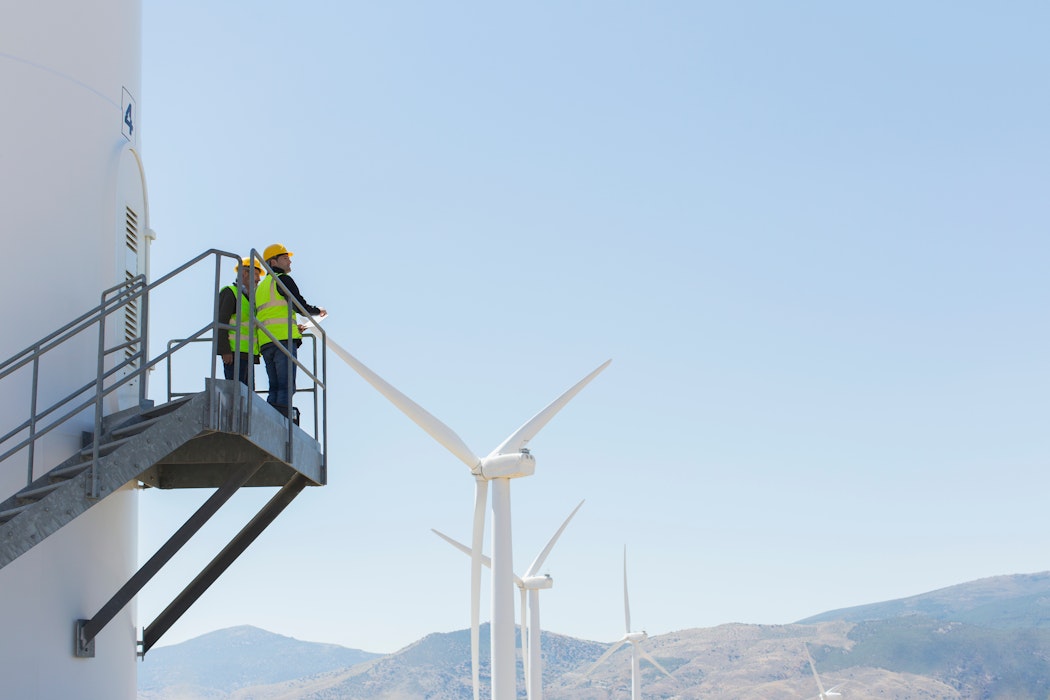 Arbeiders staan op windturbine in landelijk landschap