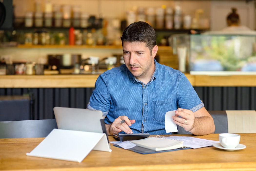 Le propriétaire d'une petite entreprise calcule les dépenses et les taxes d'une facture de restaurant en ligne