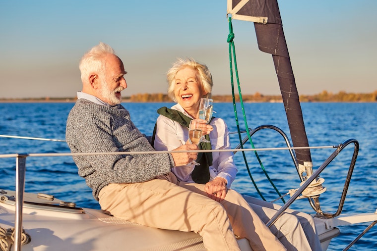 Couple heureux buvant du champagne et riant tout en se relaxant sur un voilier ou un pont de yacht.