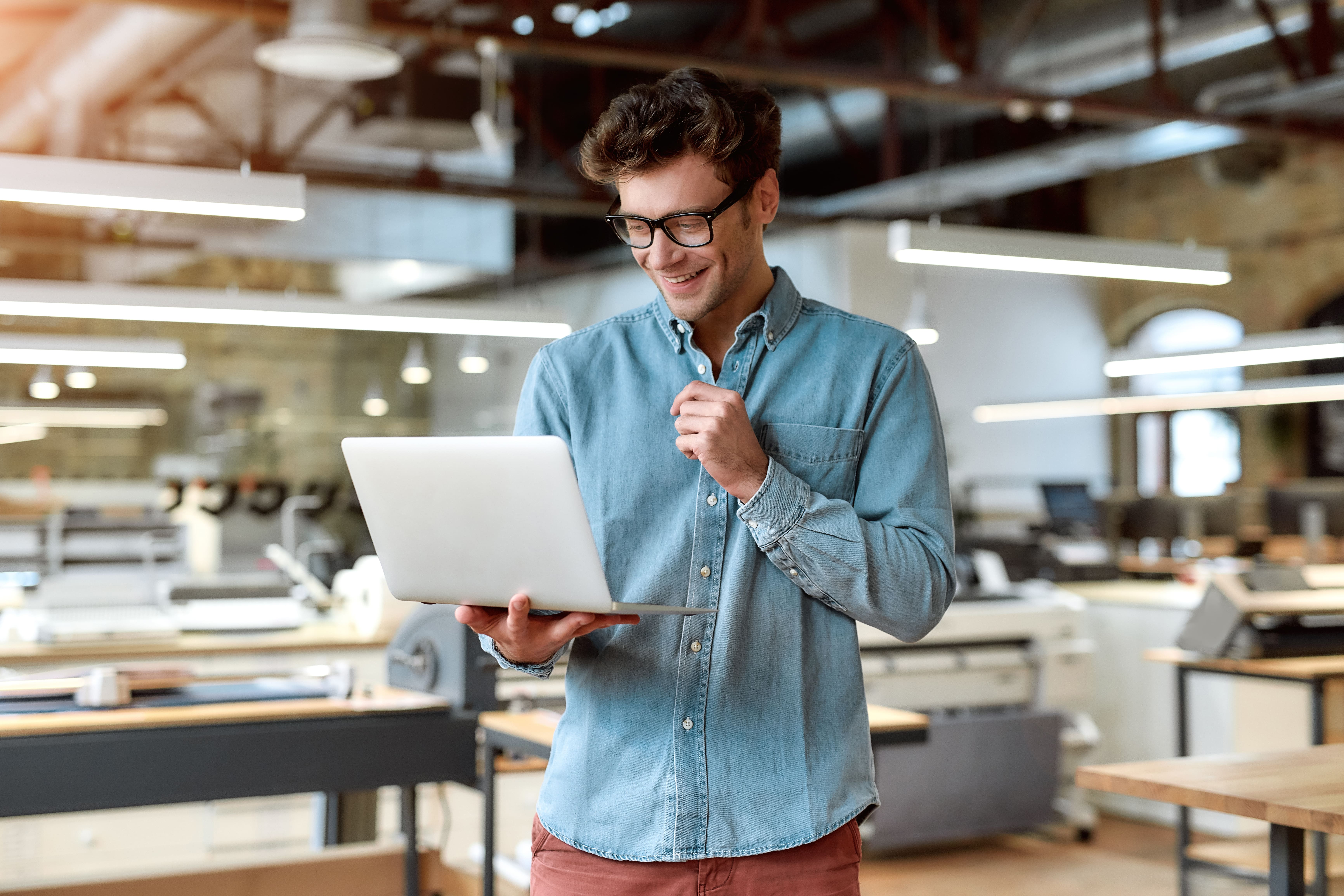 Jeune homme d'affaires debout dans un bureau avec son ordinateur portable.