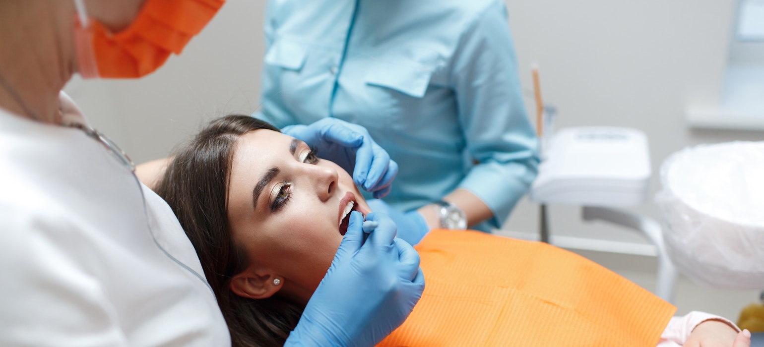 De tandarts en de assistent behandelen de tand van een patiënt.