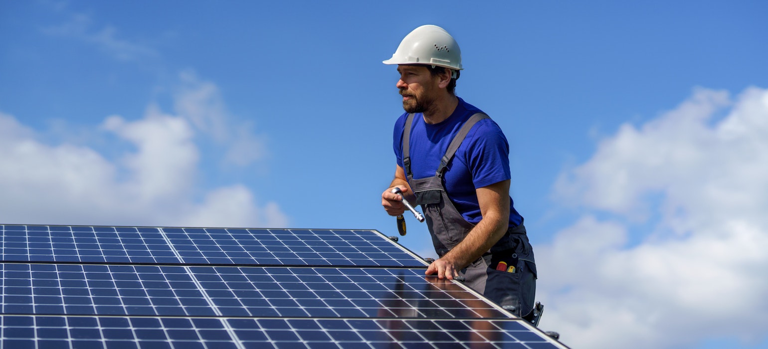 arbeider die zonnepanelen op een dak installeert