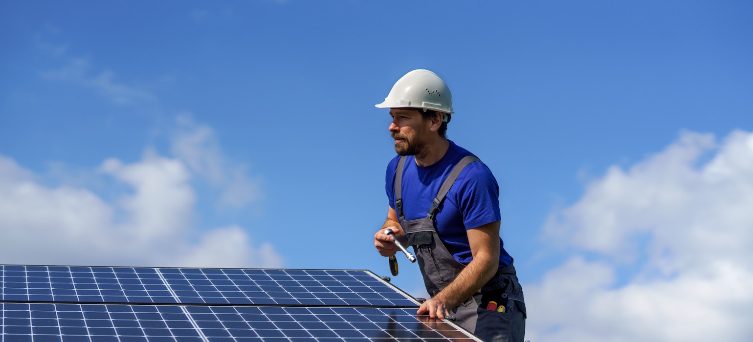 arbeider die zonnepanelen op een dak installeert