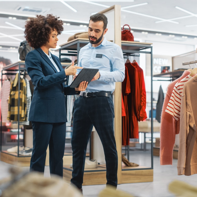 Winkelmanager praat met medewerker in kledingwinkel