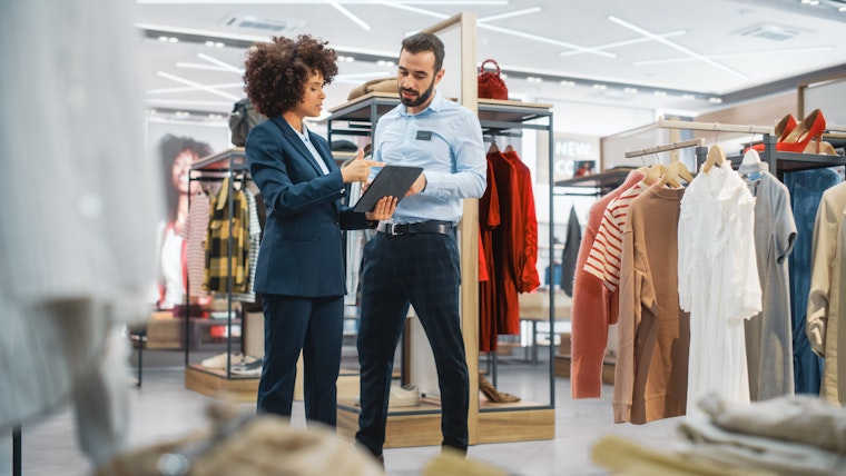 Winkelmanager praat met medewerker in kledingwinkel