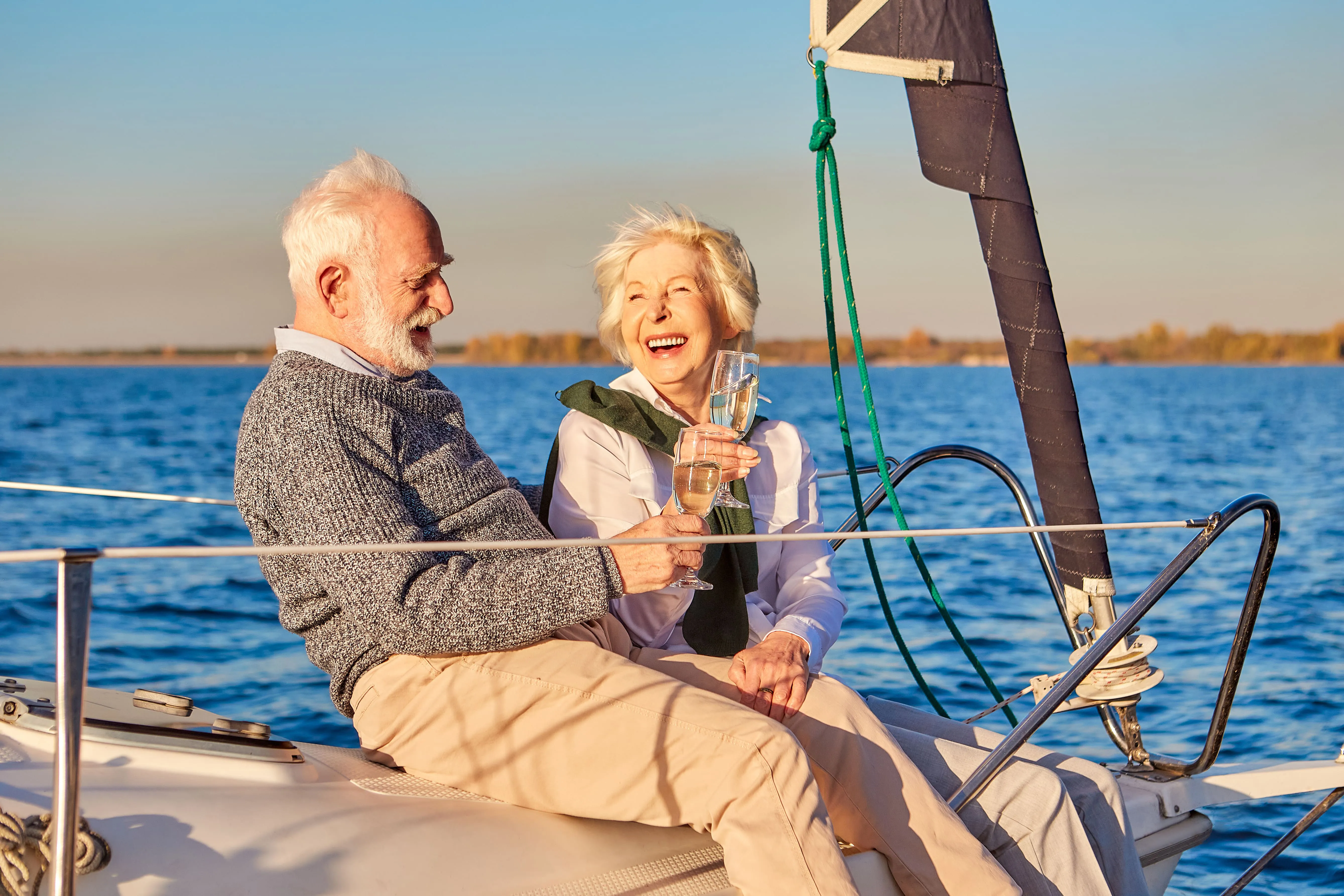 Couple heureux buvant du champagne et riant tout en se relaxant sur le pont d’un voilier ou d’un yacht.