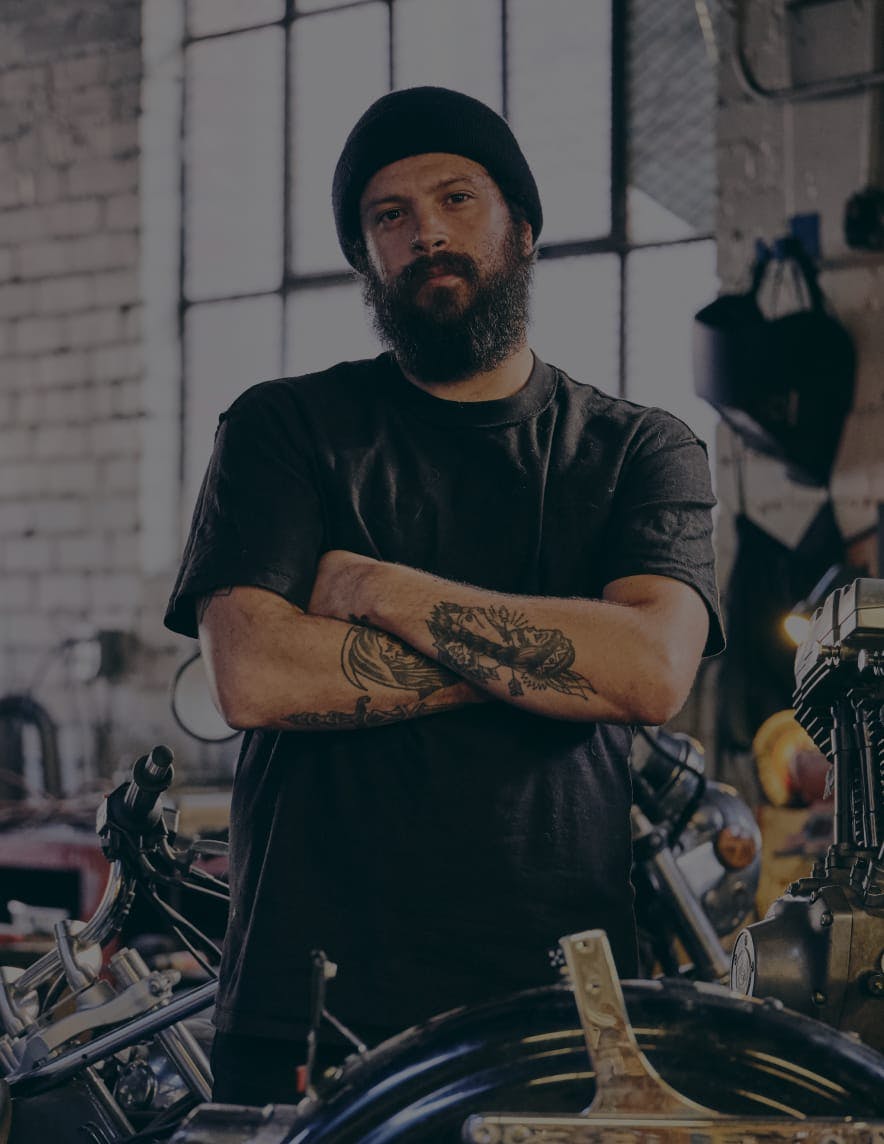 Man in a motorcycle shop posing for the camera.