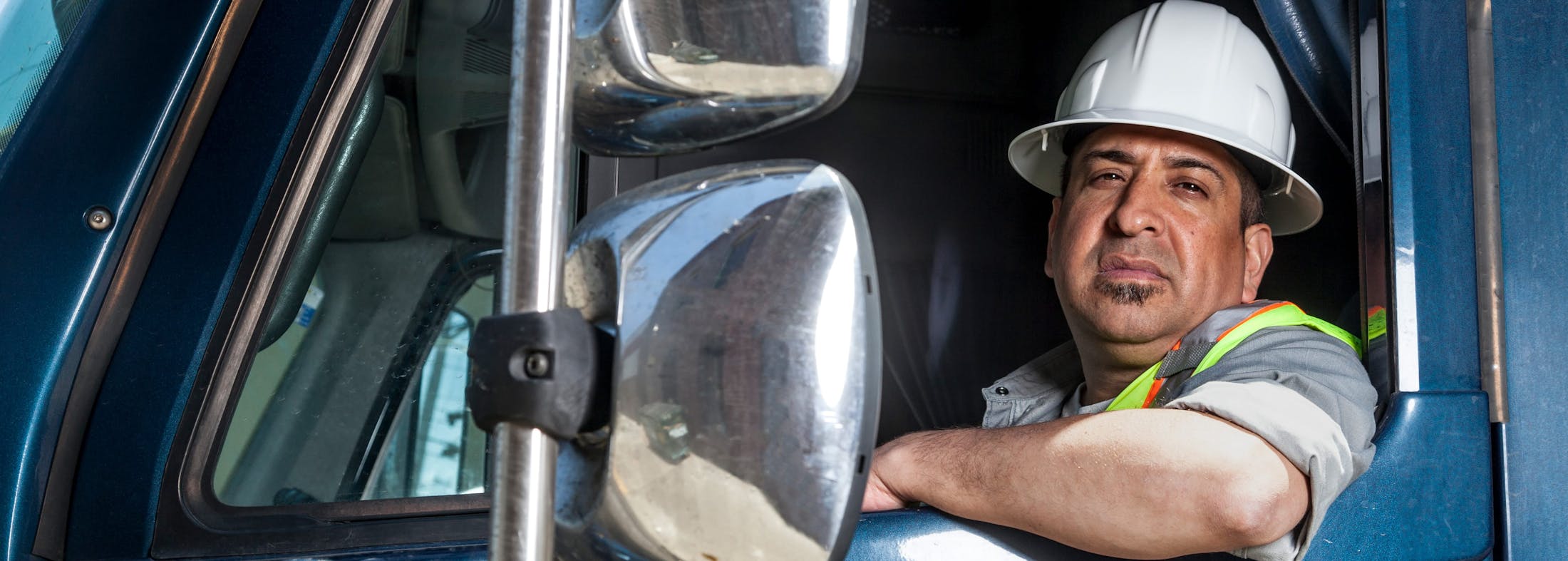 Man looking out of a big rig wearing a helmet