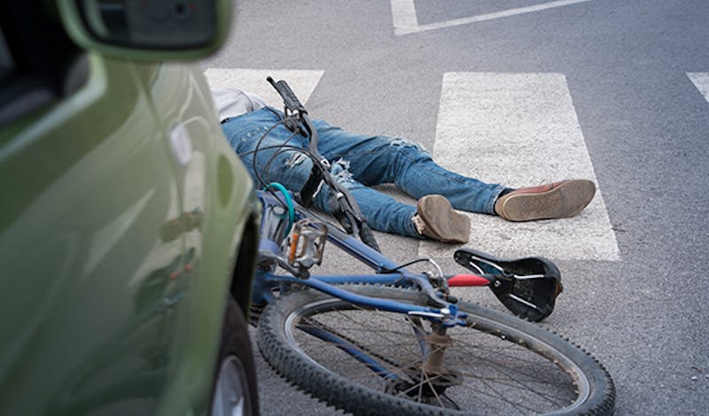 Person and bike on the ground behind a car