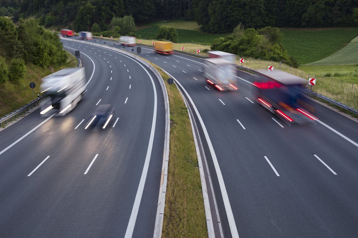 High-angle view of multiple commercial trucks and vehicles traveling on a divided highway