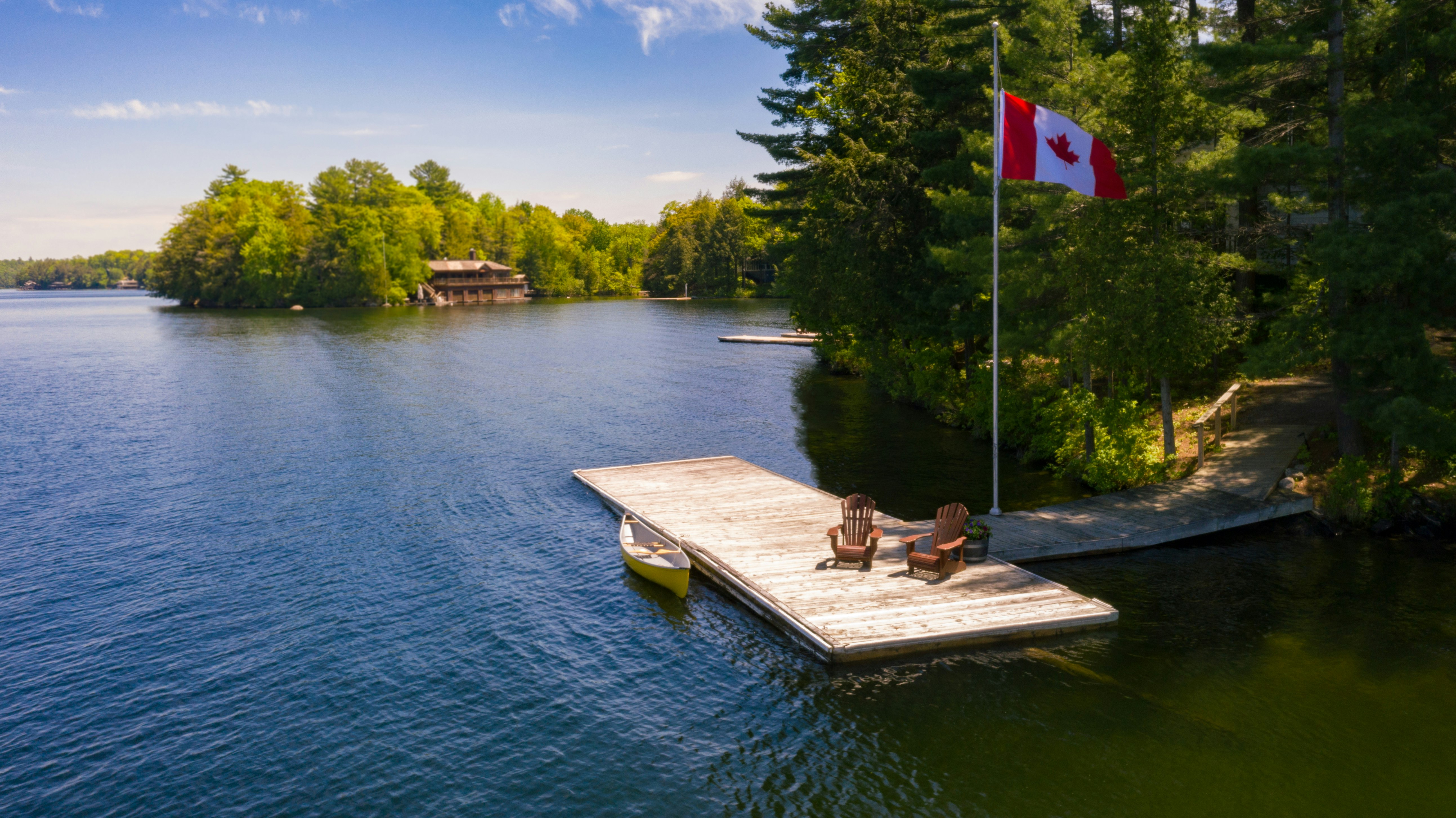 Retirement in Canada A dock at a lake in Ontario with two chairs and a canoe.
