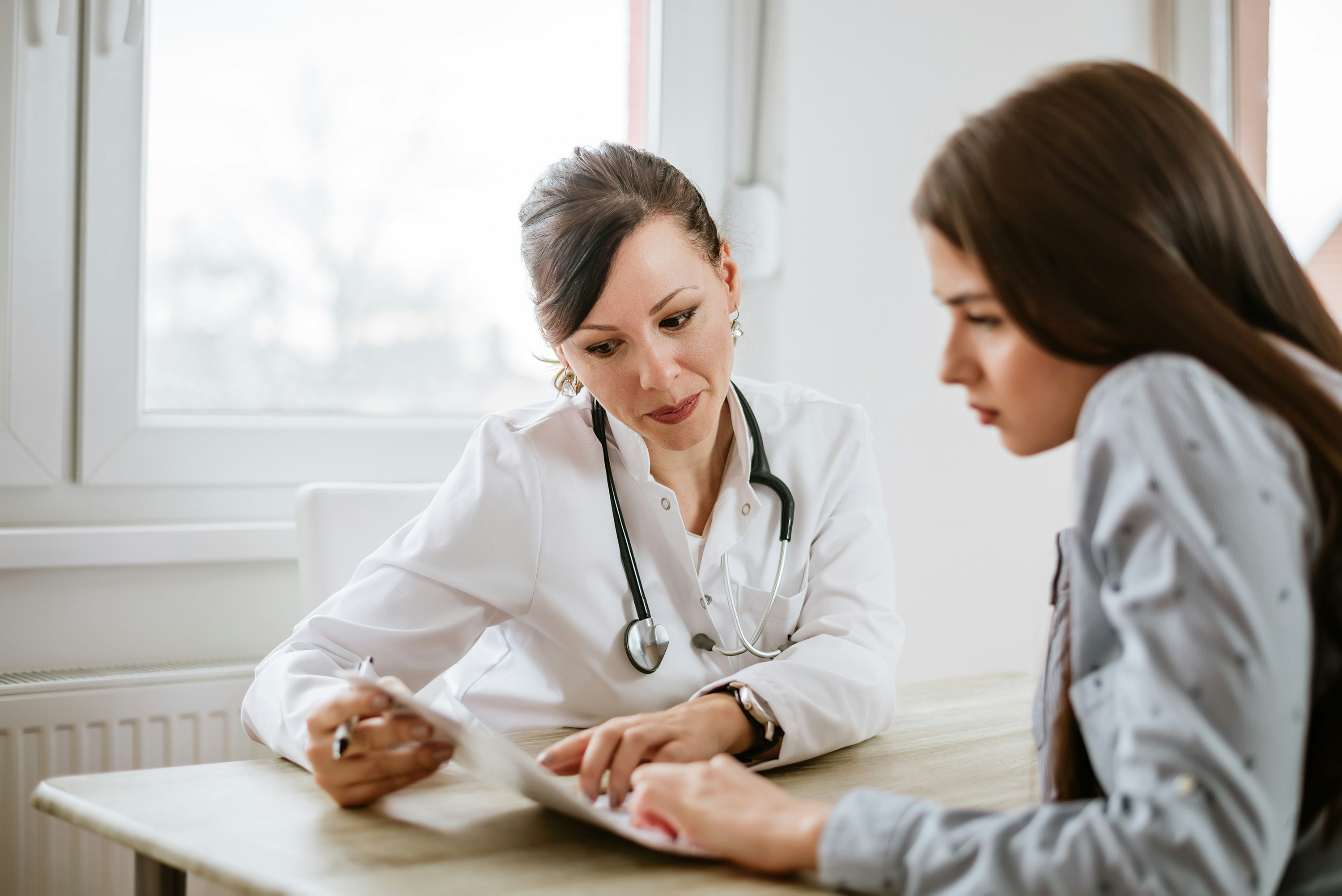 A woman doctor points to the chart of her patient.