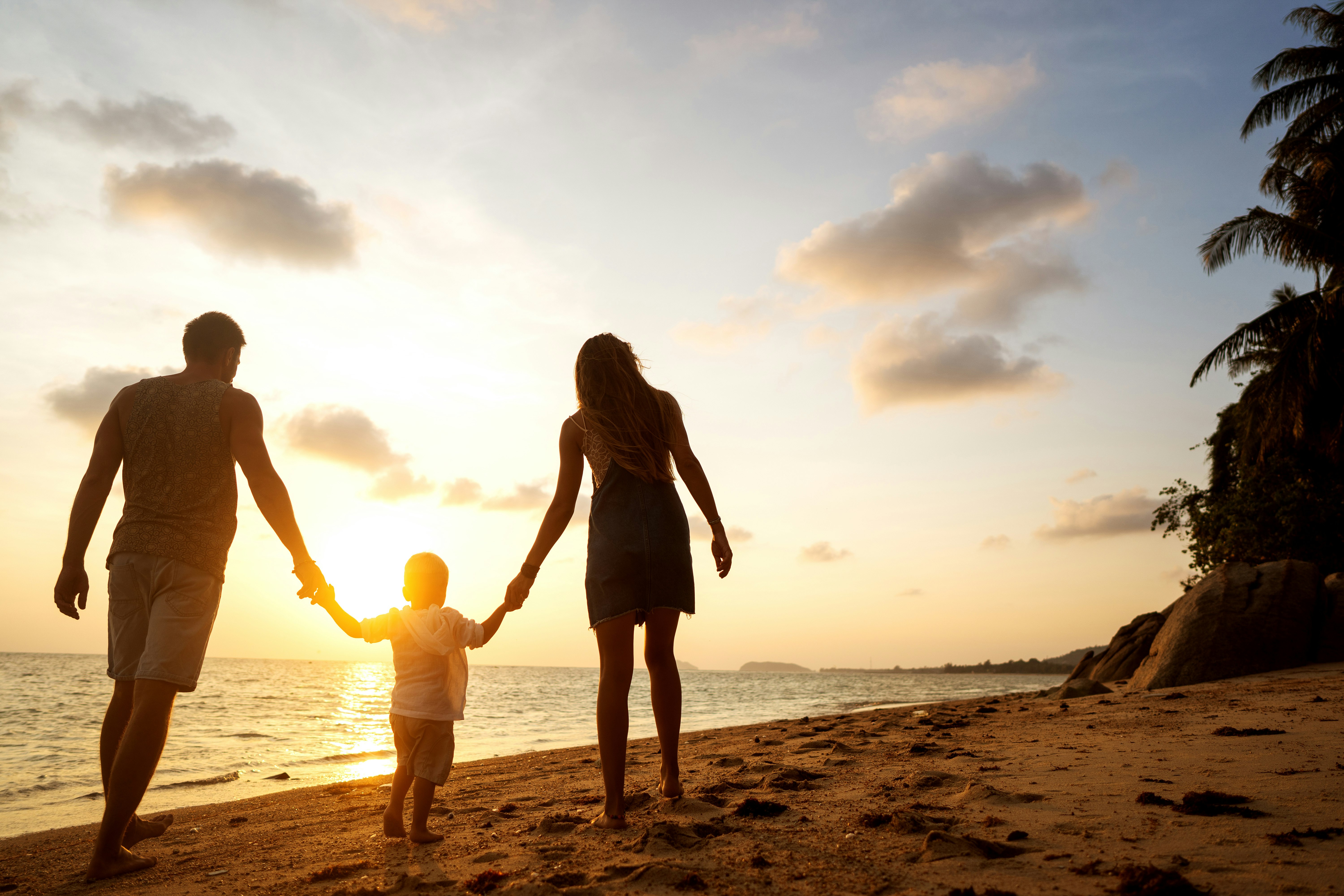 Family vacation Family holds hands on the beach in a tropic destination.