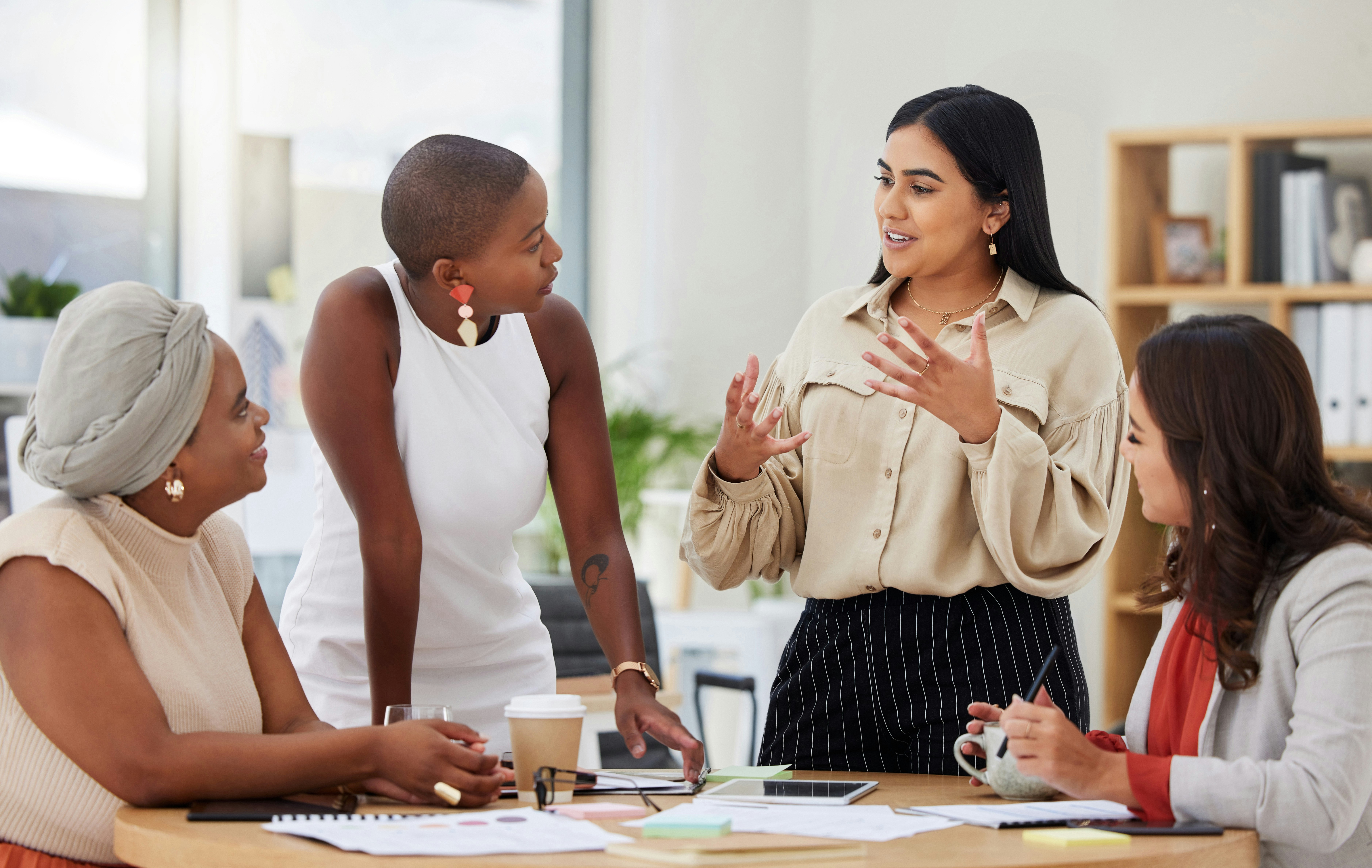 Group of young women in business meet at an office table.