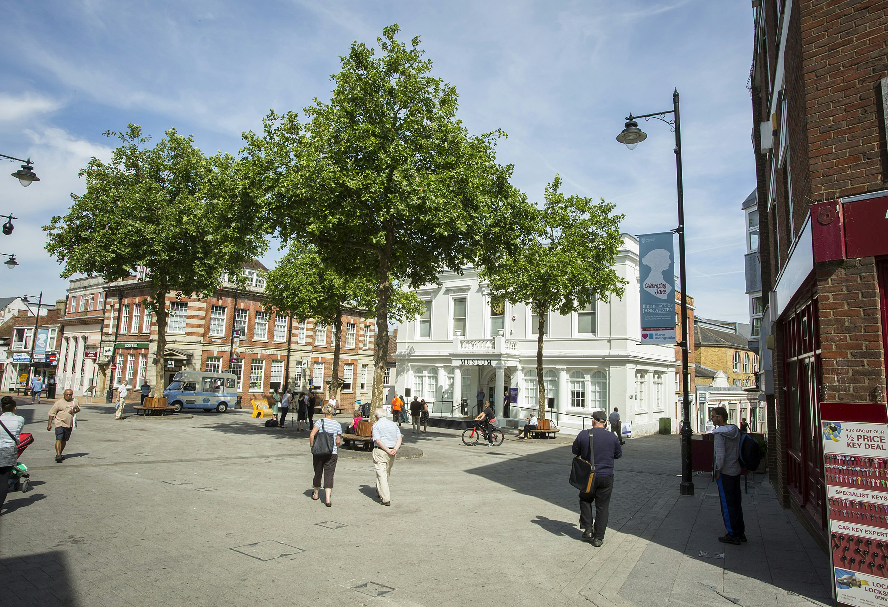 A white building with three trees in front and market square.