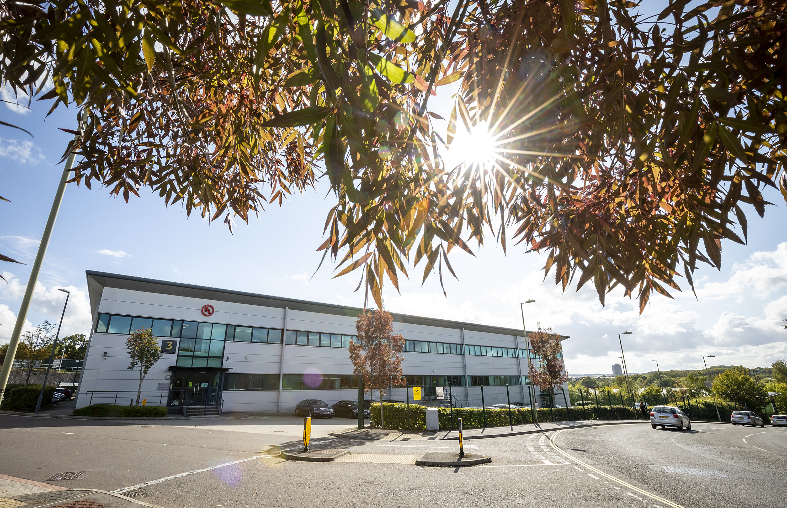 A panelled and glass office block. To the right is a busy road