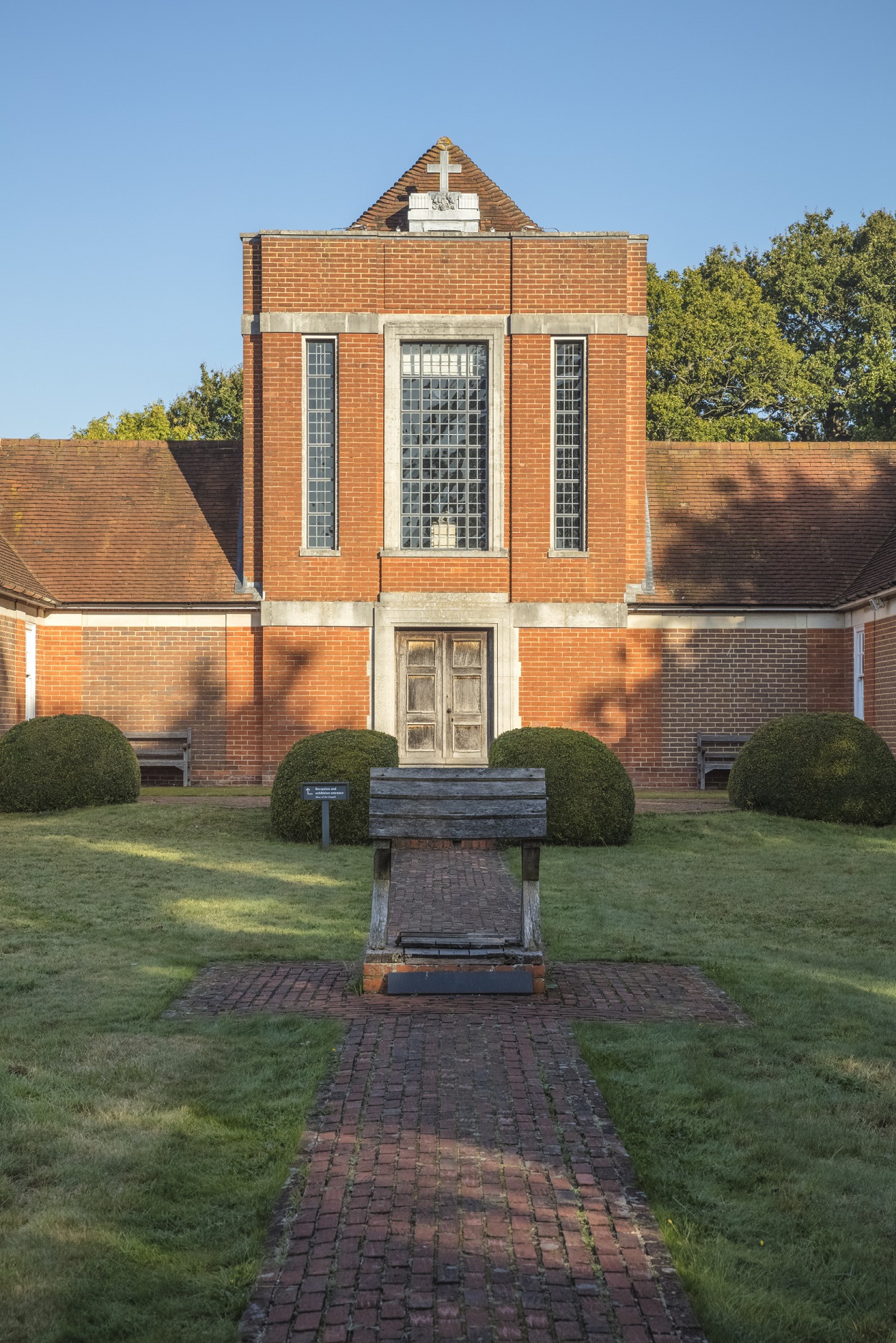 A red brick facade of the Sandham Memorial Chapel. This is two storey in the middle and drops down to single storey