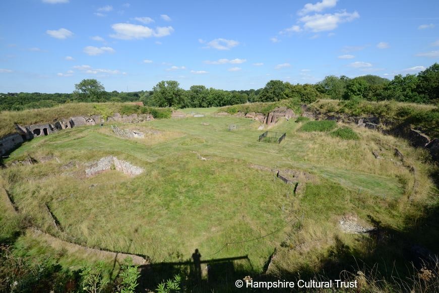 A green grassed area with ruins sticking up