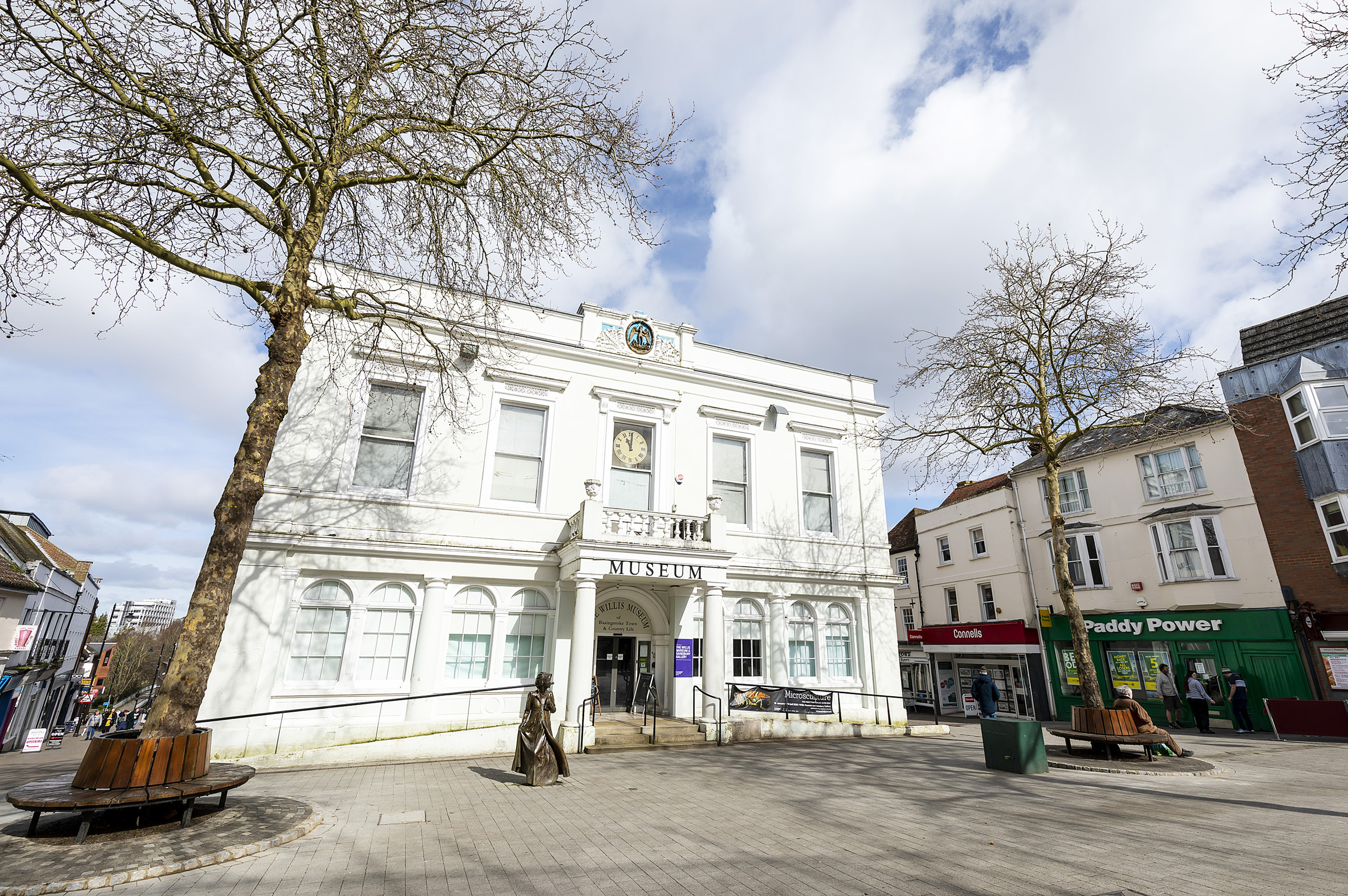 A white building with three trees in front and market square.