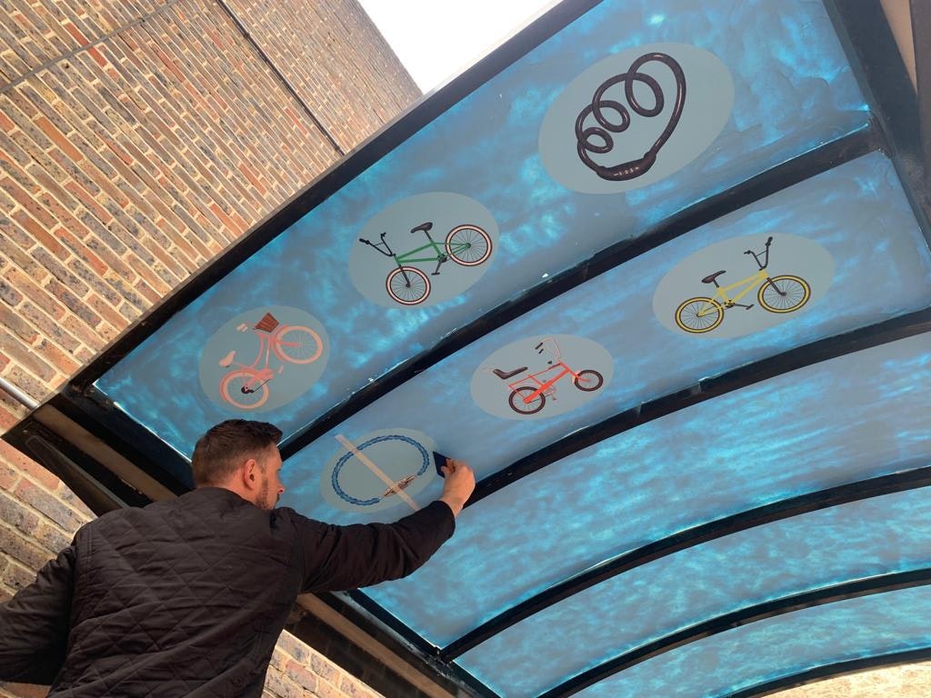 Neil Jepson is painting the ceiling of a public cycle shelter
