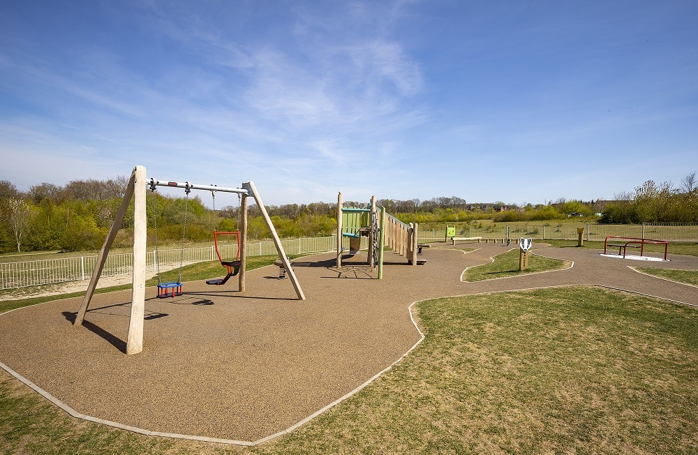 A wooden swingset and climbing frame pictured on a sunny day.