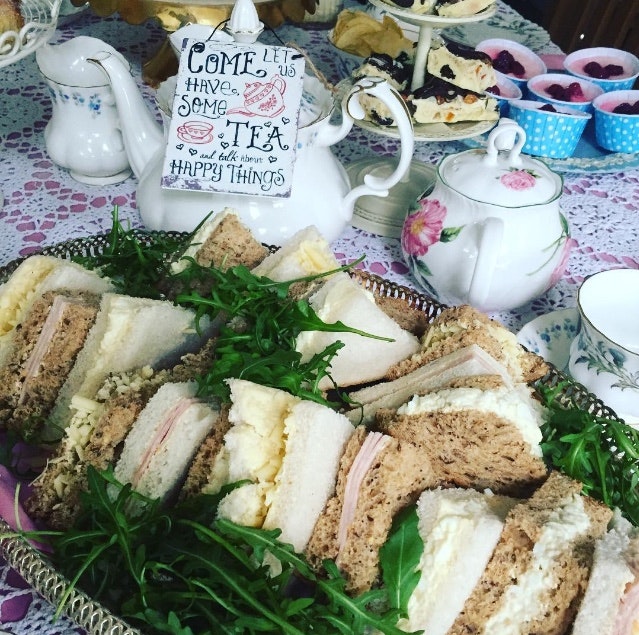 Platter of sandwiches, tea pot, tea cup and saucers