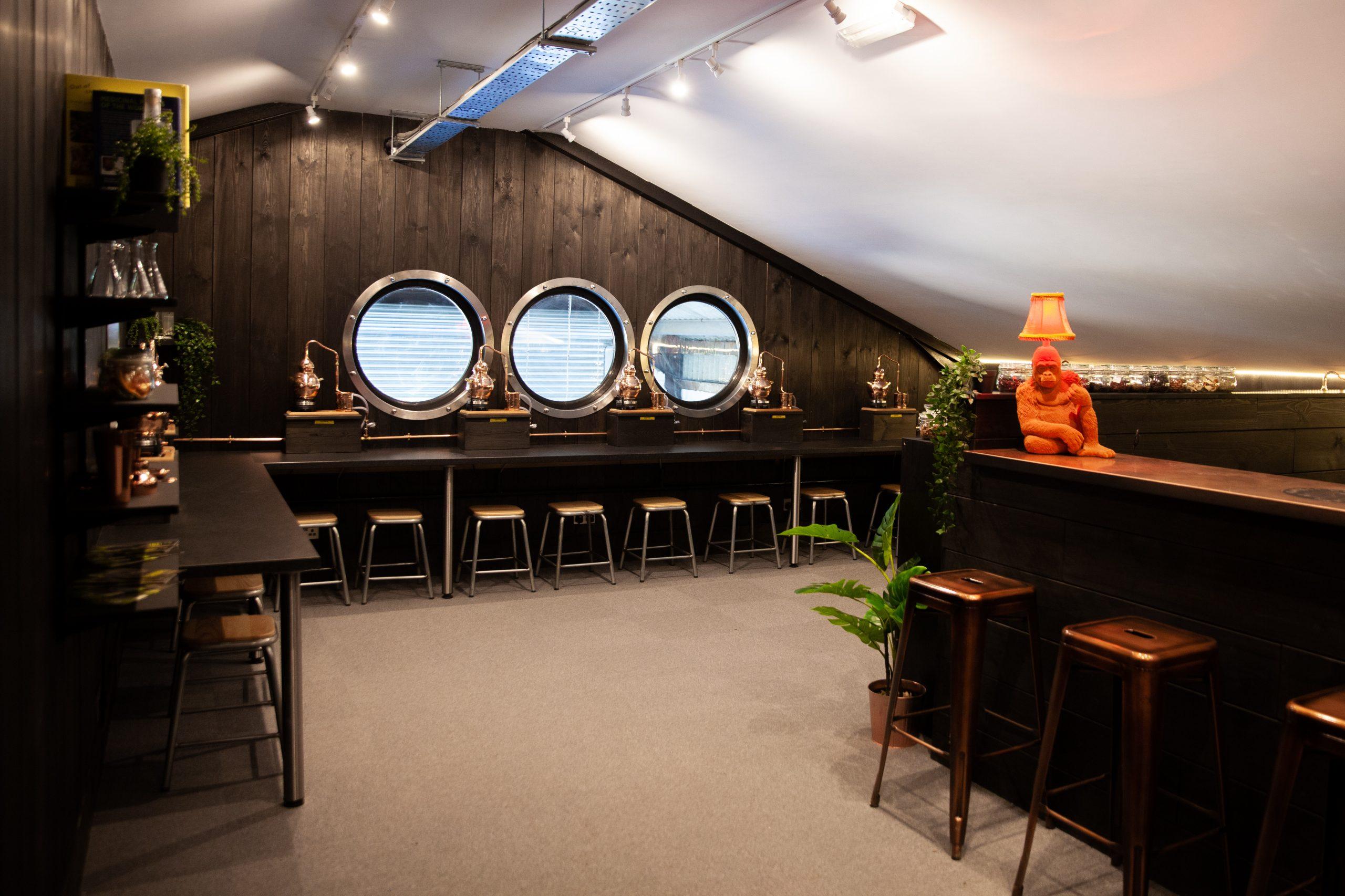 Gorilla Spirits Co. Distillery - a room inside with dark wood paneling and bar stools up against tables.