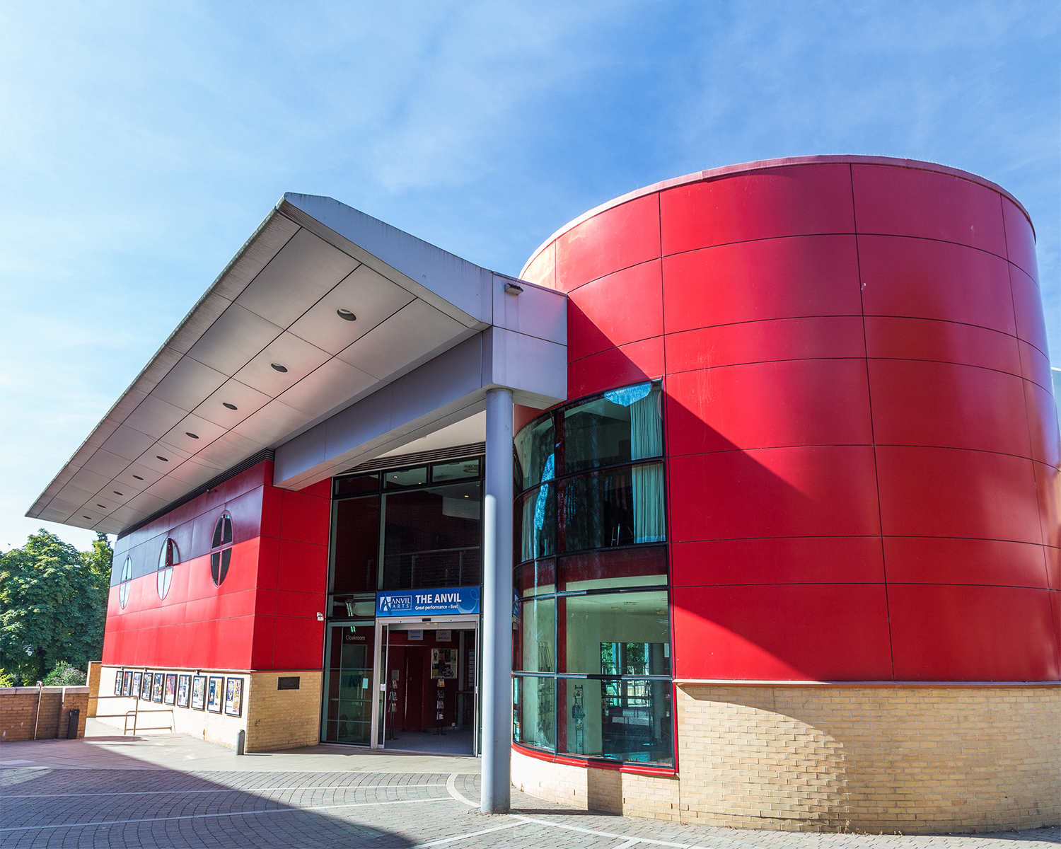 A red and brick building with large glass windows and a silver canopy.