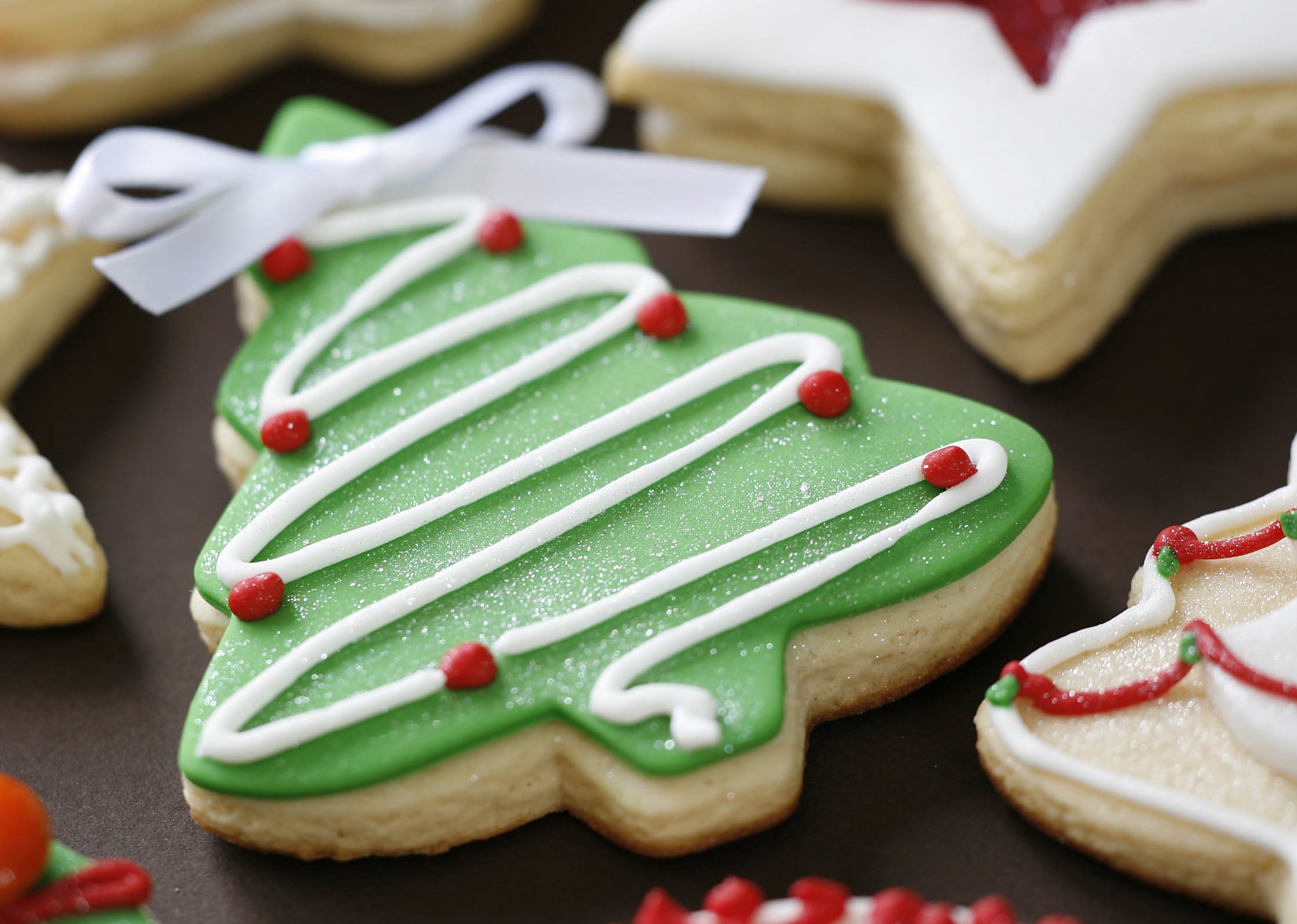 a biscuit in the shape of a tree with green icing and white and red decorative icing.
