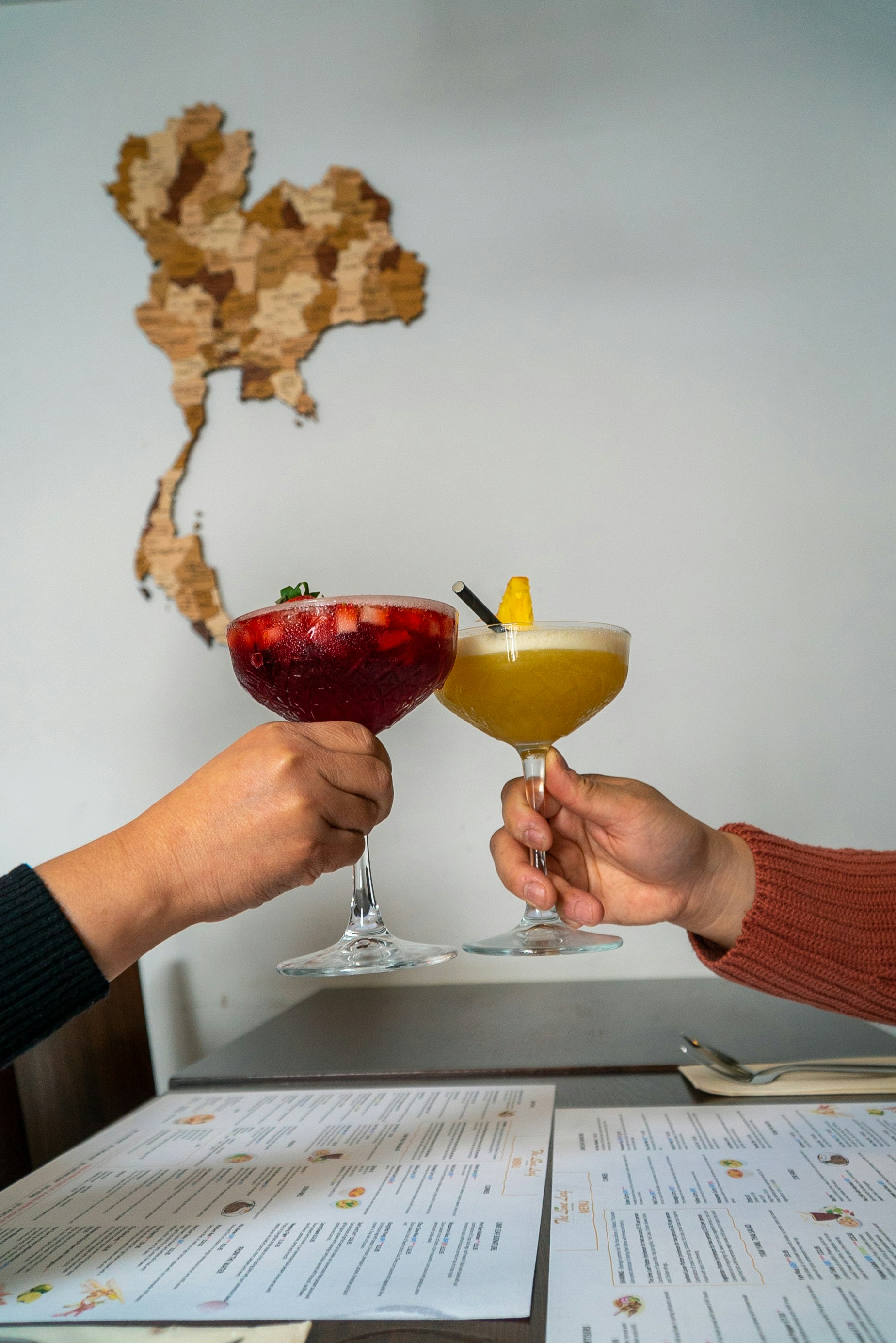 Two people hold up cocktails