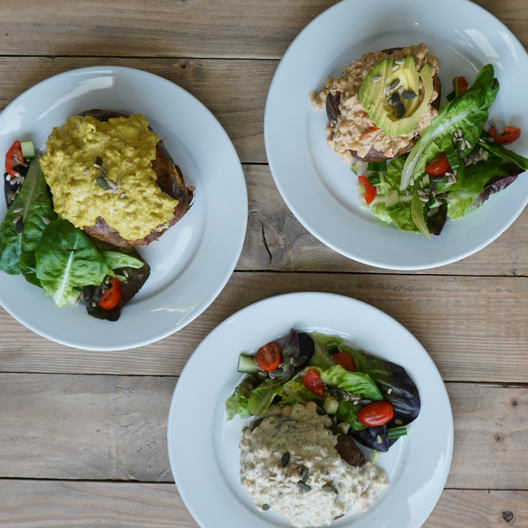 Three white plates packed with colourful vegan dishes.