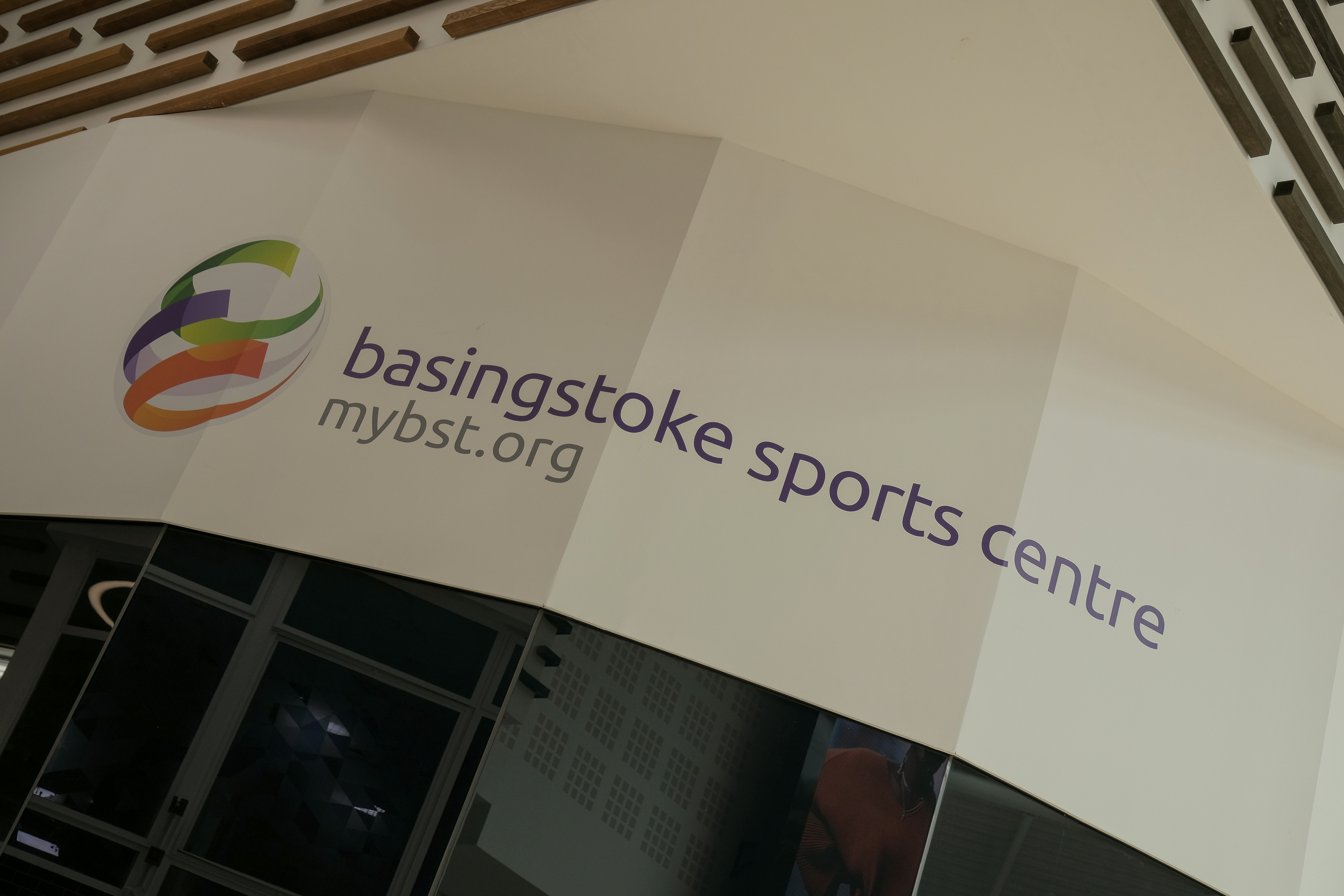 A white sign with basingstoke sports centre. mybst.org on it