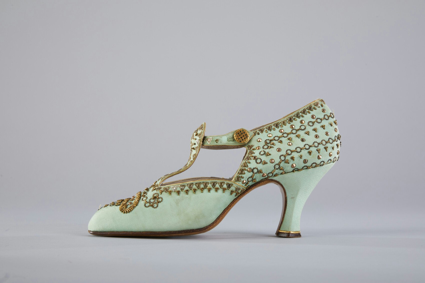 A minty green shoe with a point and a heel. It has gold stitching.