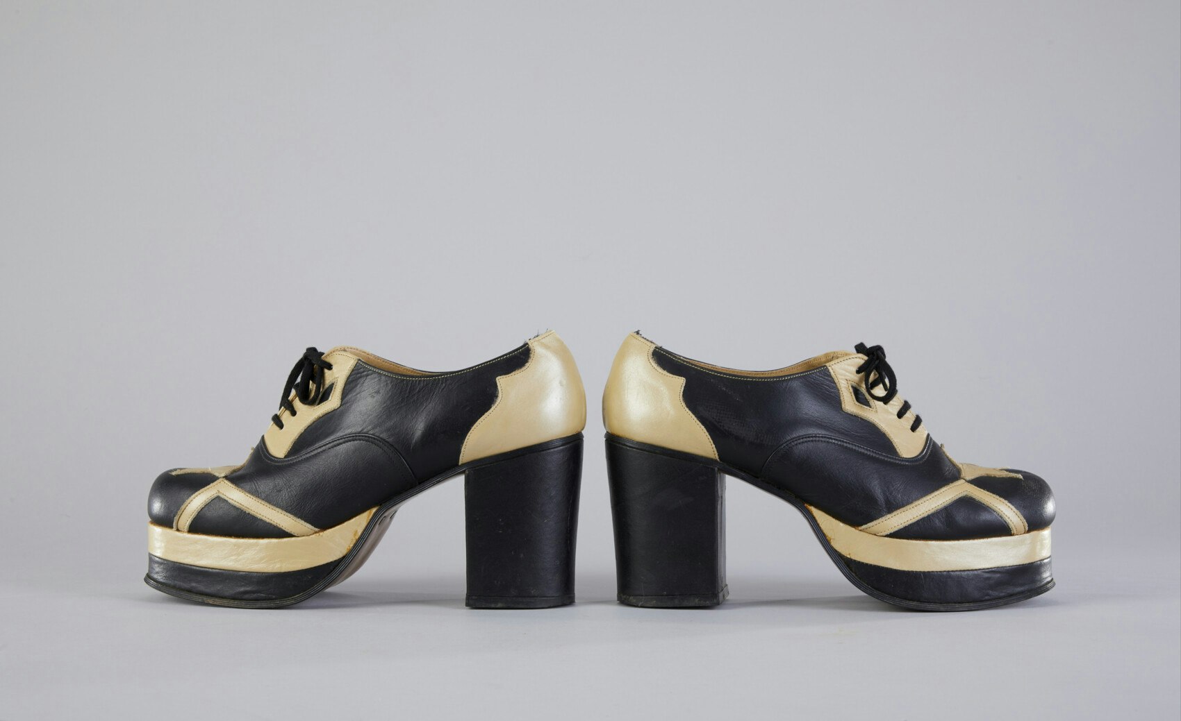 A pair of platform shoes that are black and cream.