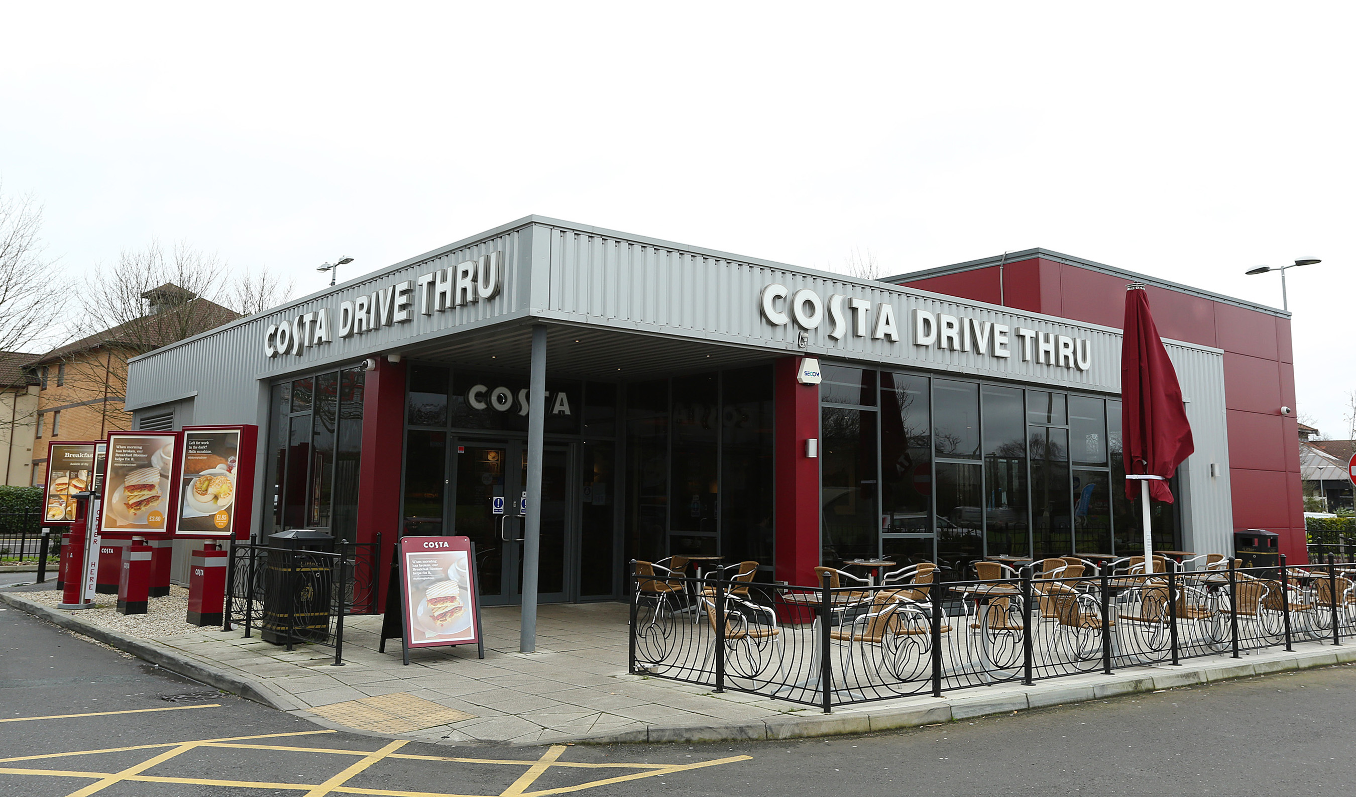 A deep red and silver building. Some outside seating and umbrellas.