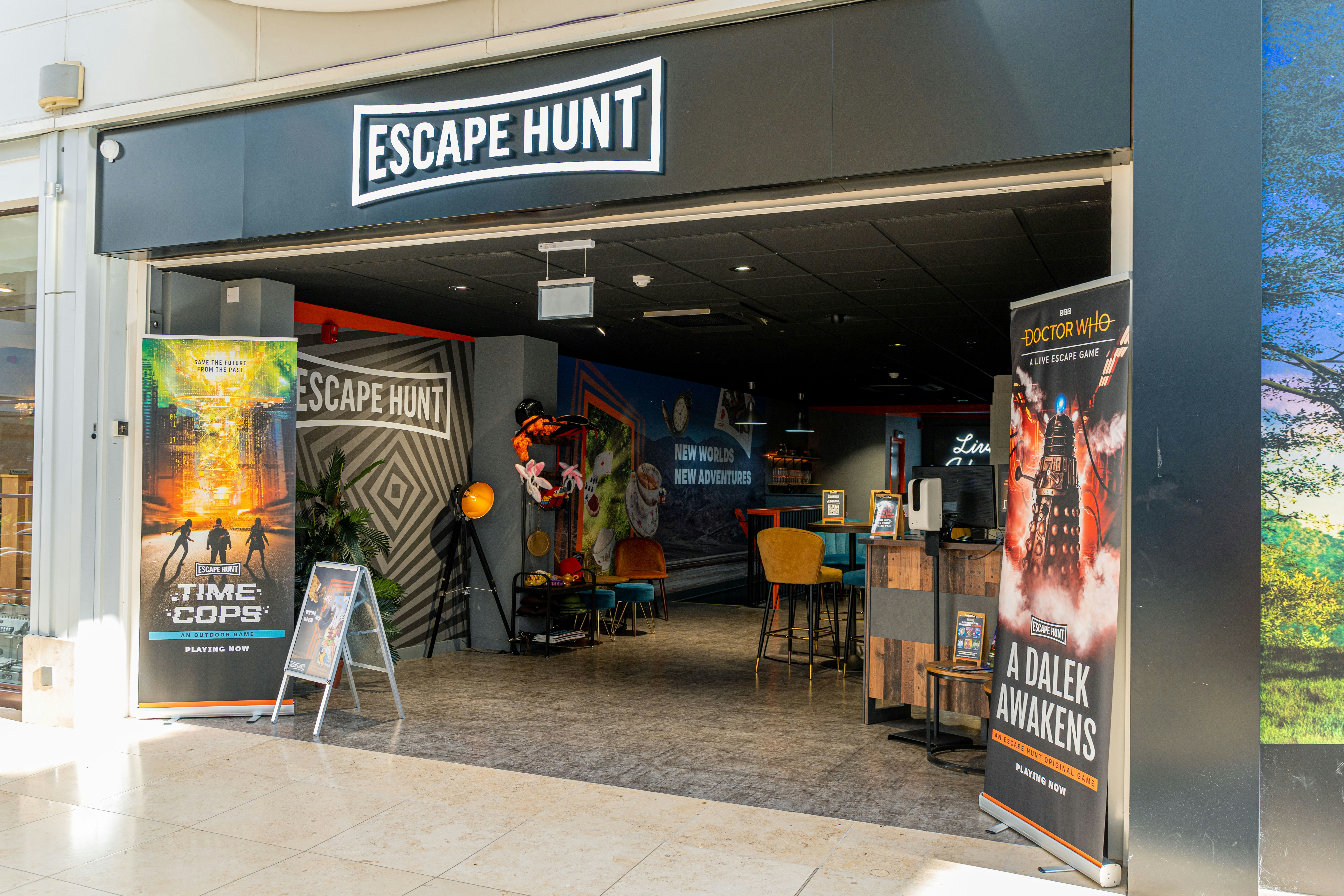 A black archway shop front reads Escape Hunt, you can see inside with various pop-up posters, seating and a desk.