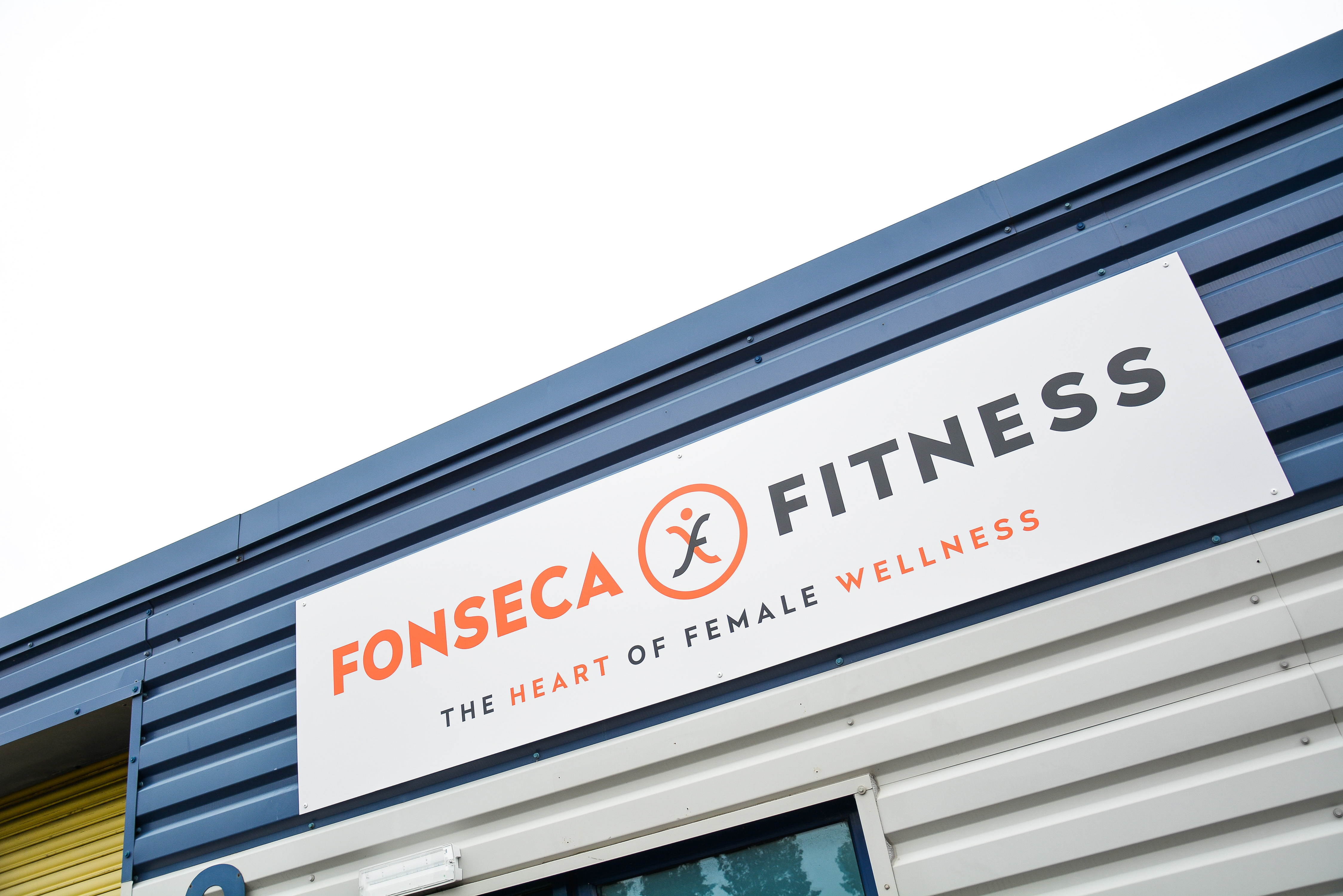 The outside of the building. A blue and white building with the sign Fonseca Fitness. The heart of female wellness.