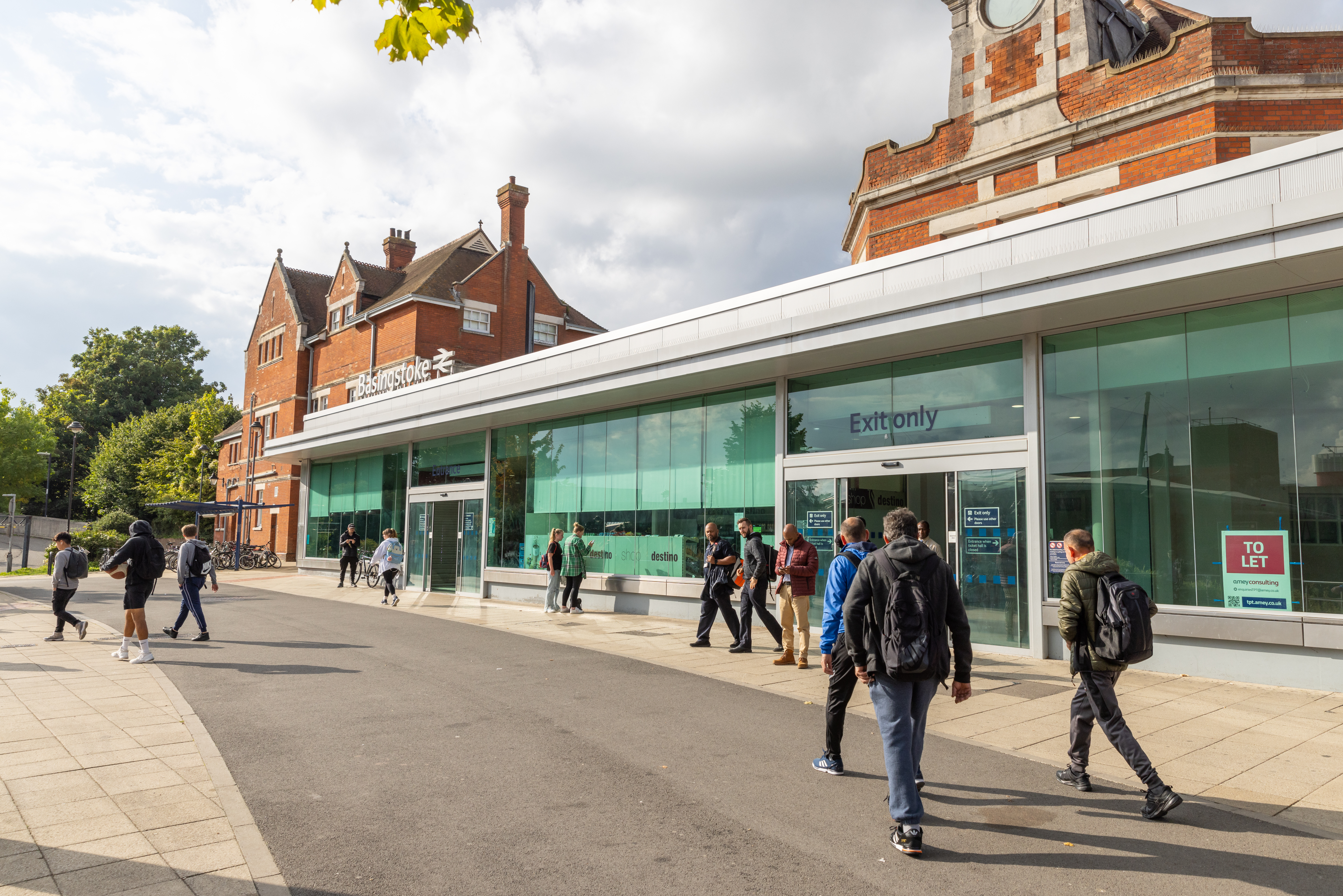 The outside of the train station, a glass and steel front with a red brick behind.