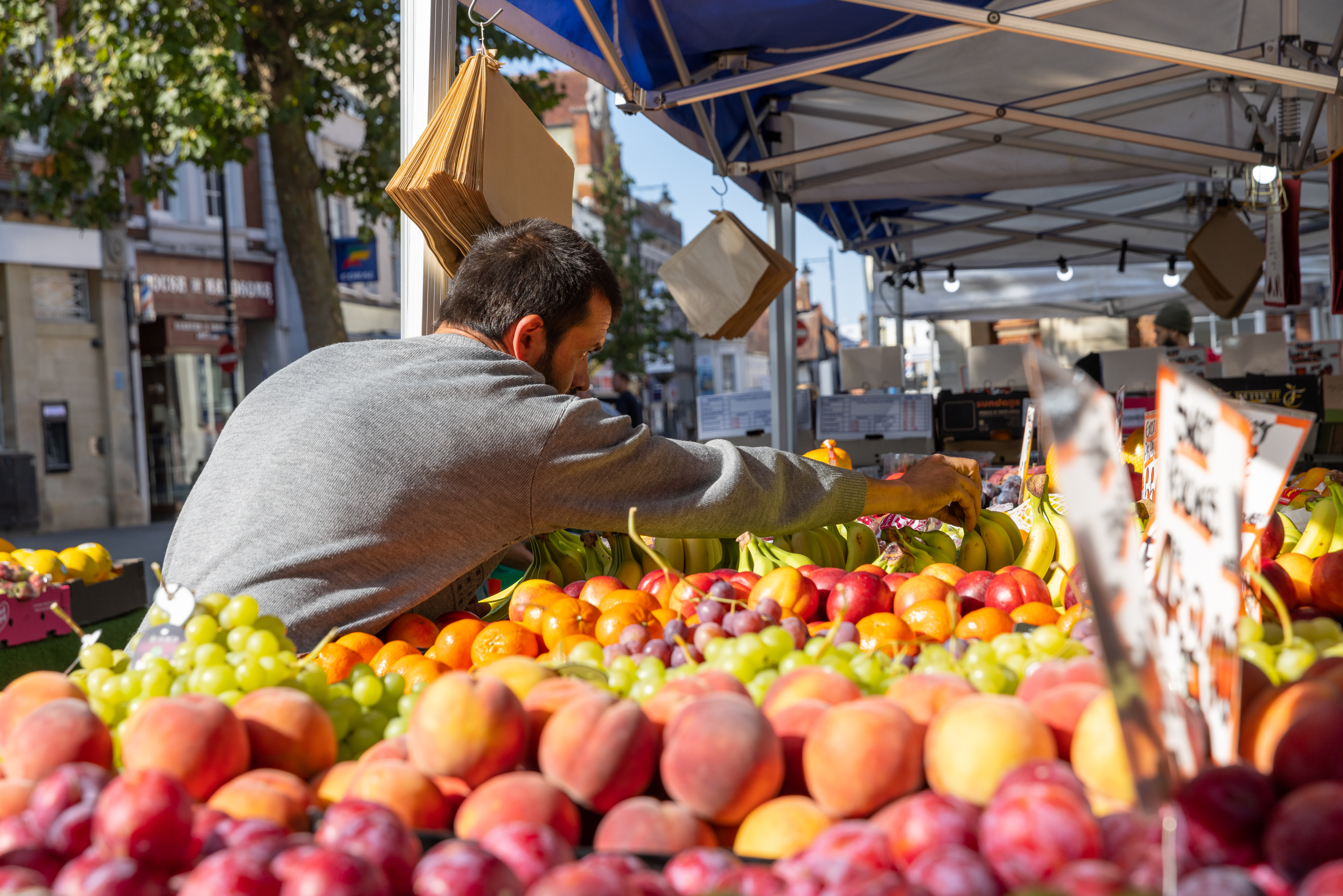 A man stands over a fruit stall.
