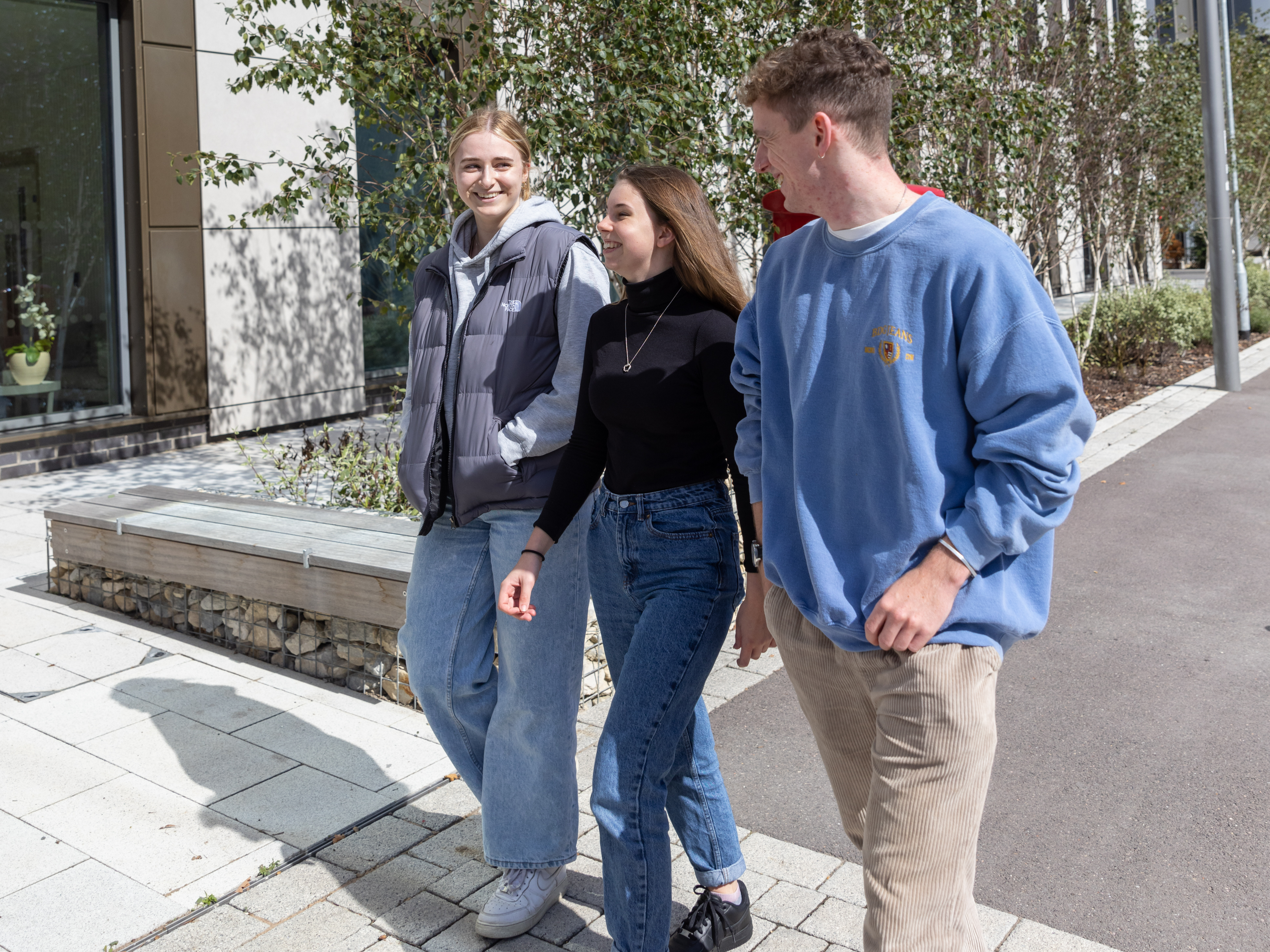 Three young people walk along interacting with each other.