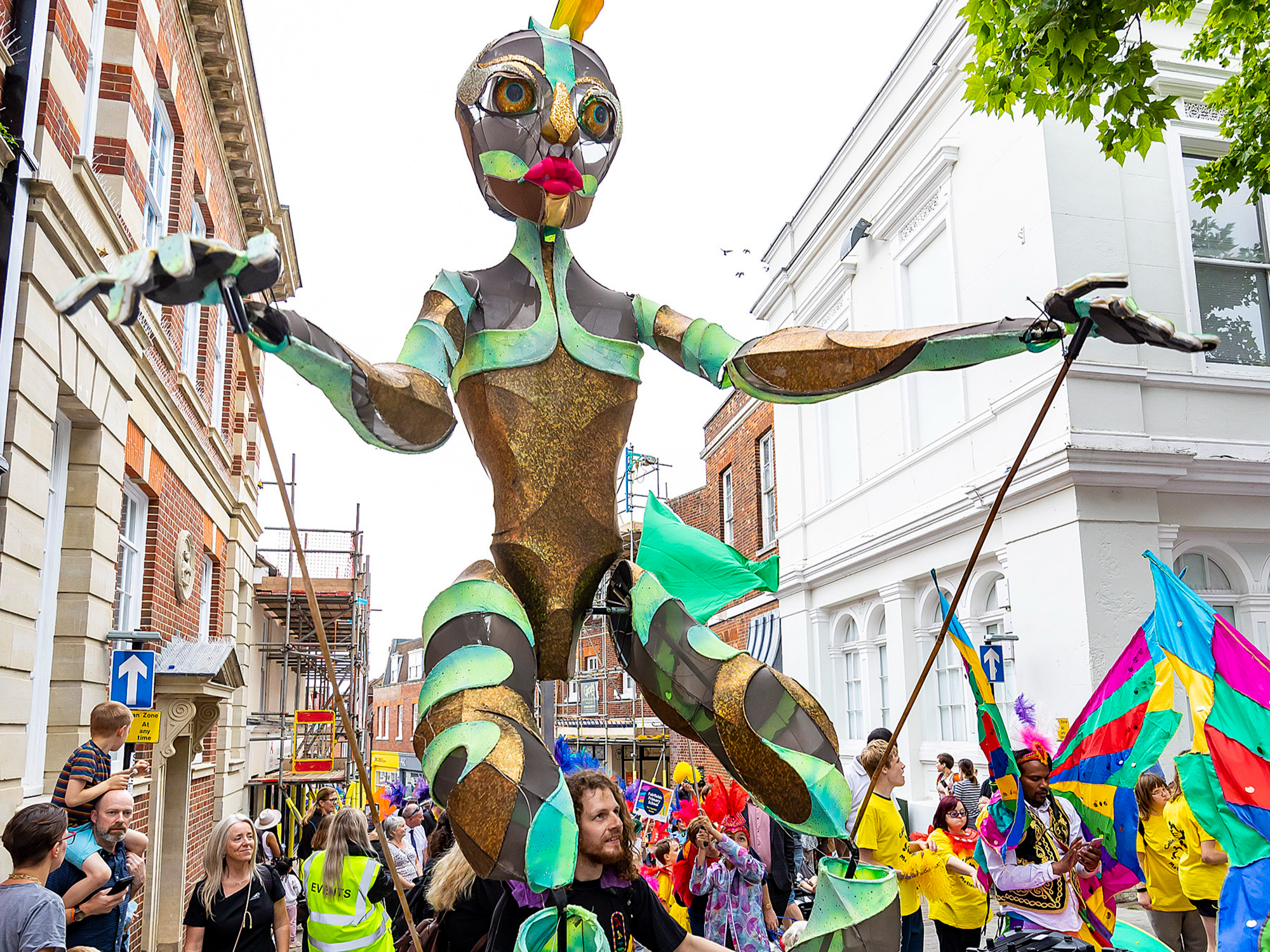 A large puppet is held in front of those in the parade.