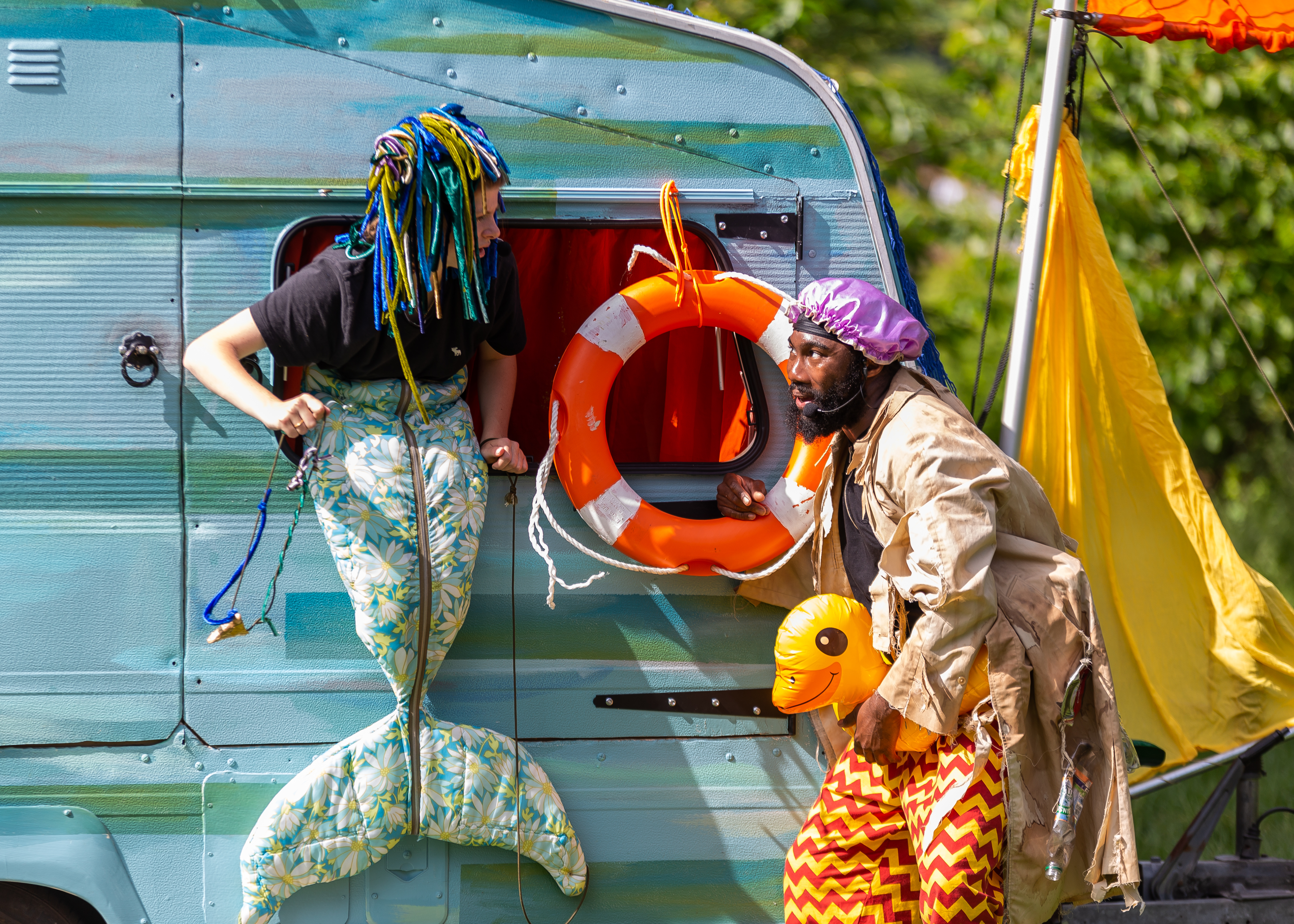 Two people are by a caravan.