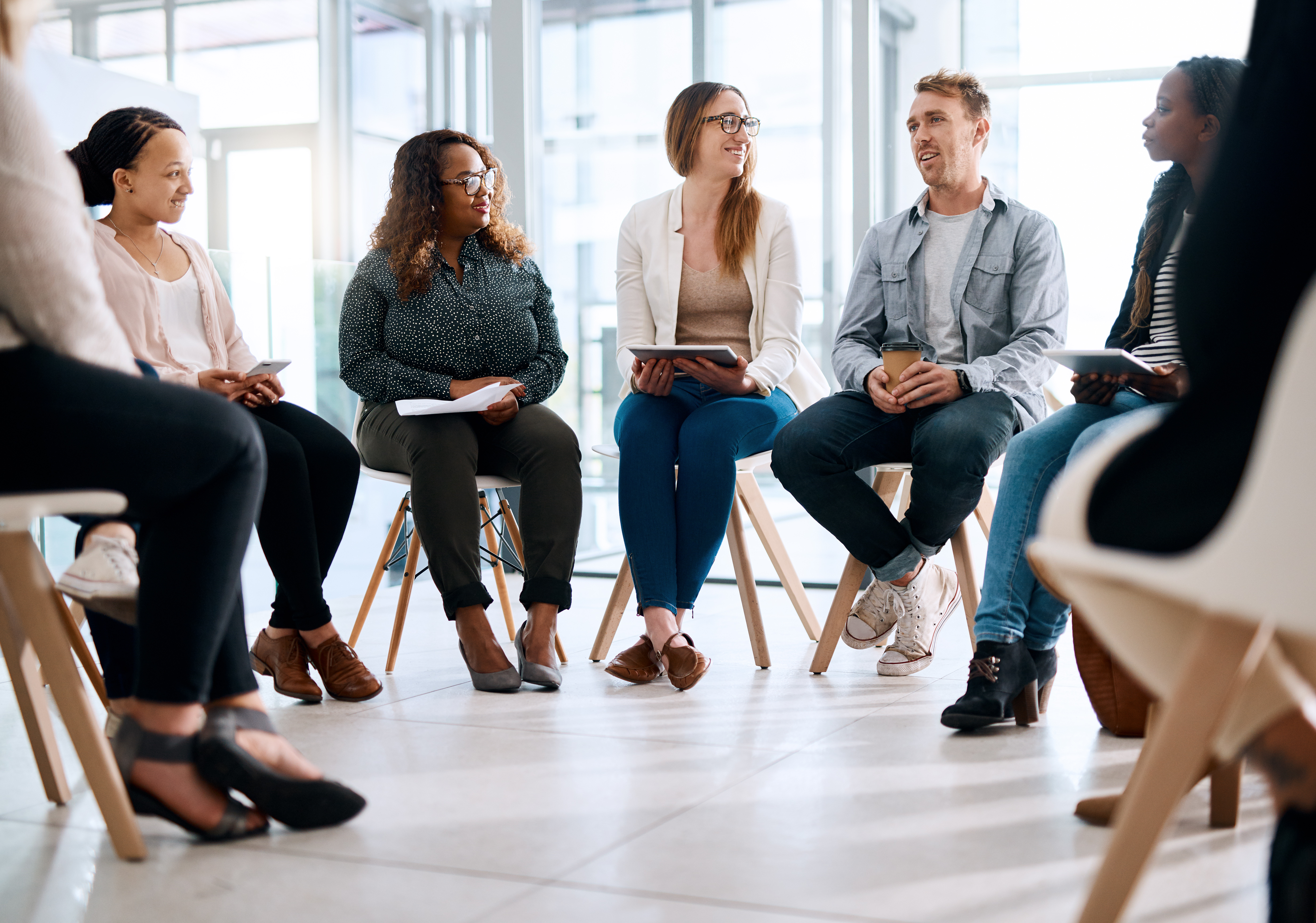 A group of work people sit on chairs in a circle chatting.