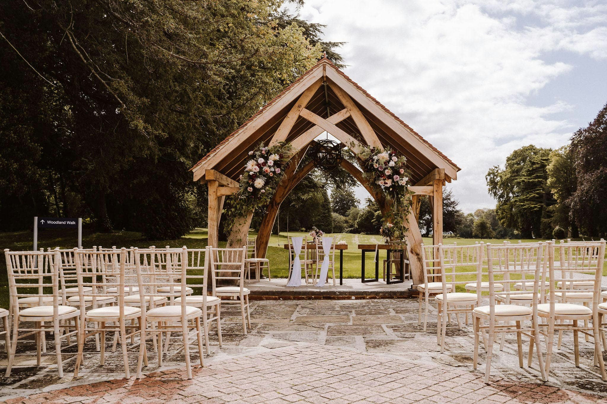 A wooden gazebo in the grounds of the hotel with chairs laid out.