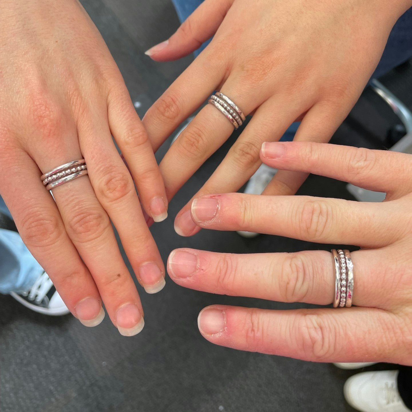 Three hands are in the image, each with a set of three stacking rings on.